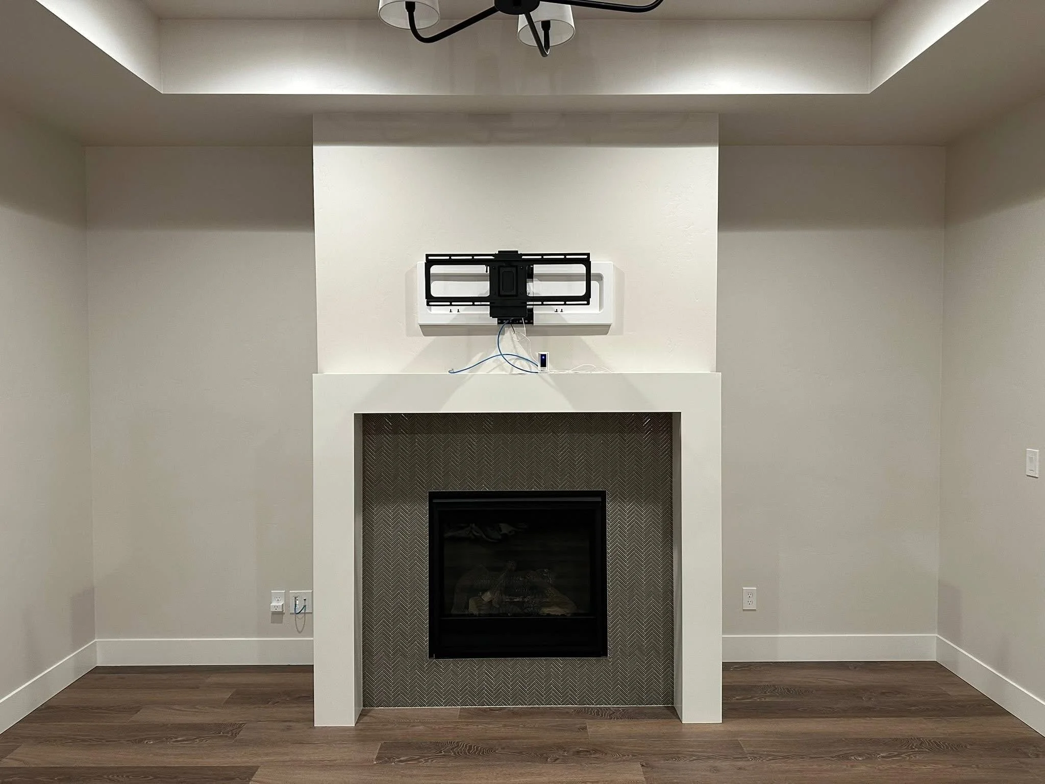 Modern fireplace feature wall with a clean white surround, herringbone tile, and TV mount ready for a custom entertainment center in Nampa, Idaho.