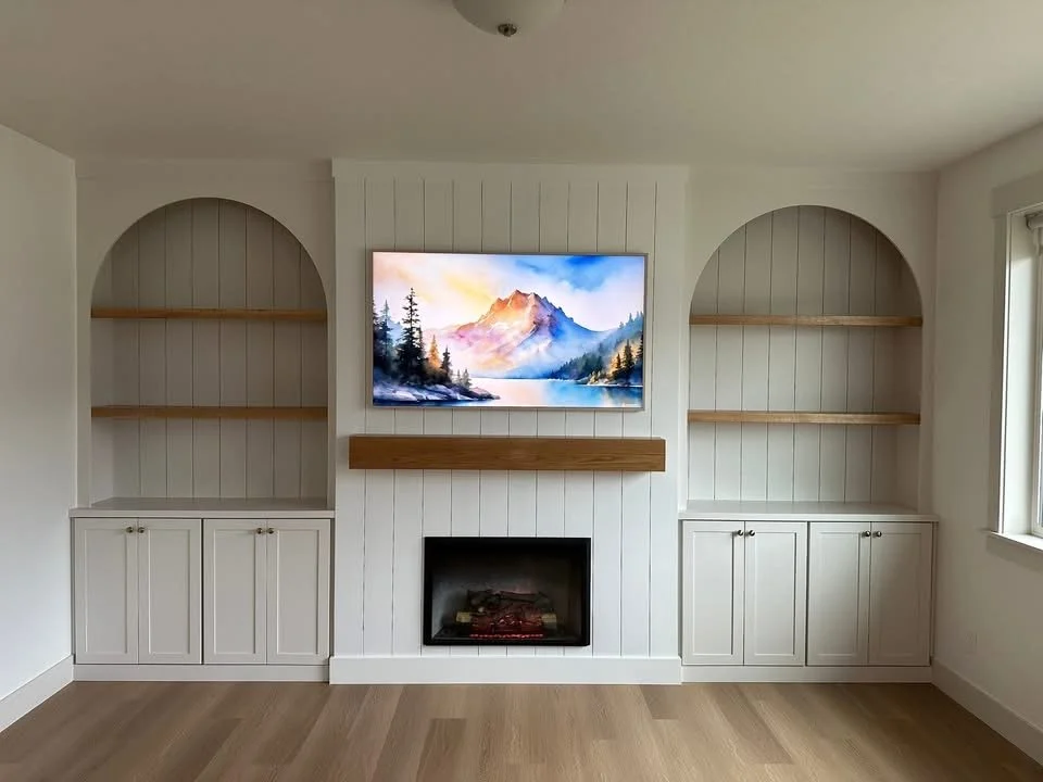 Custom entertainment center with arched built-in shelving, shiplap fireplace, floating wood mantel, and base cabinets in a Meridian, Idaho home.