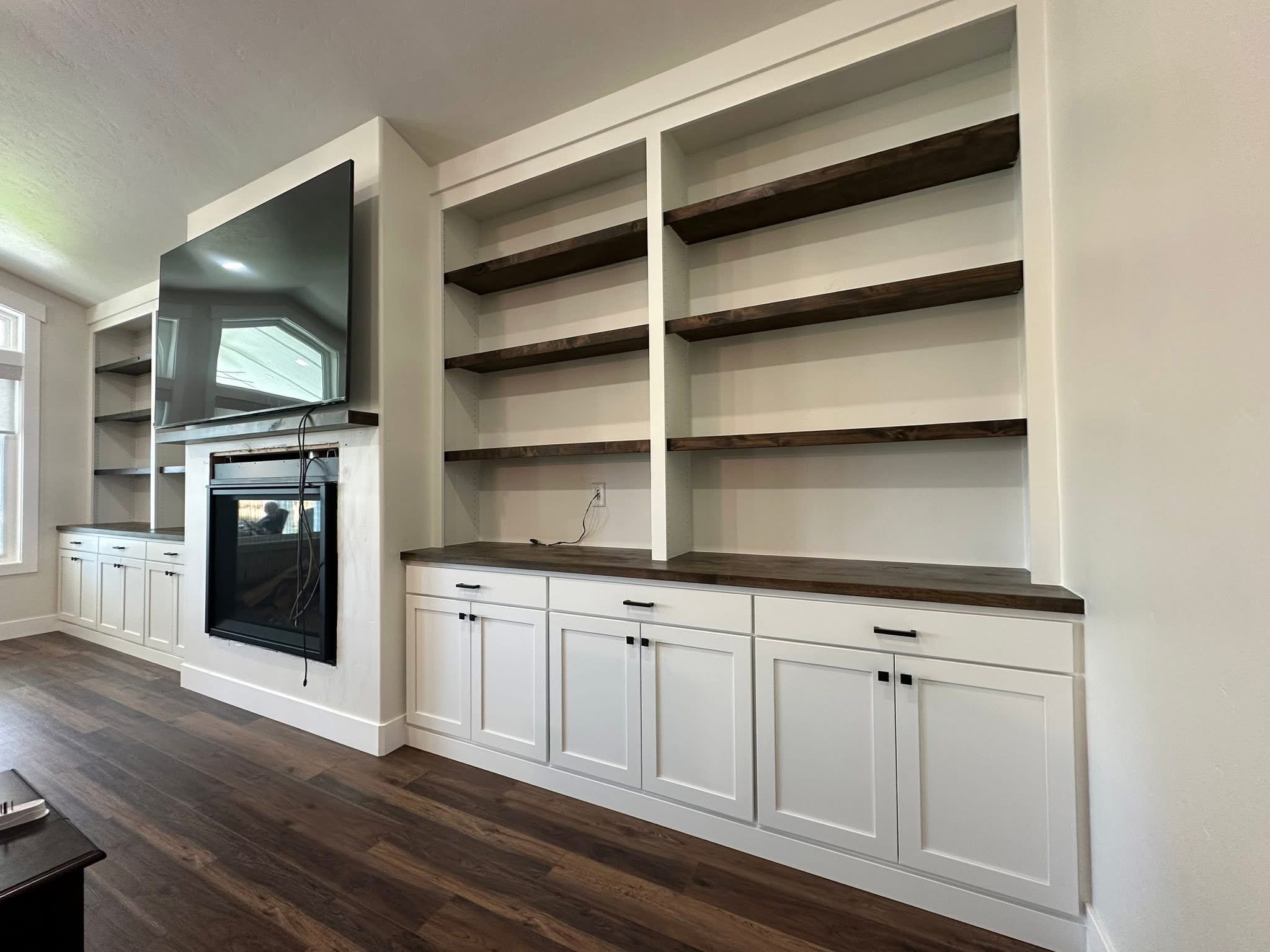 Custom white built-in bookshelves with dark wood shelves and shaker base cabinets in Wilder, Idaho.