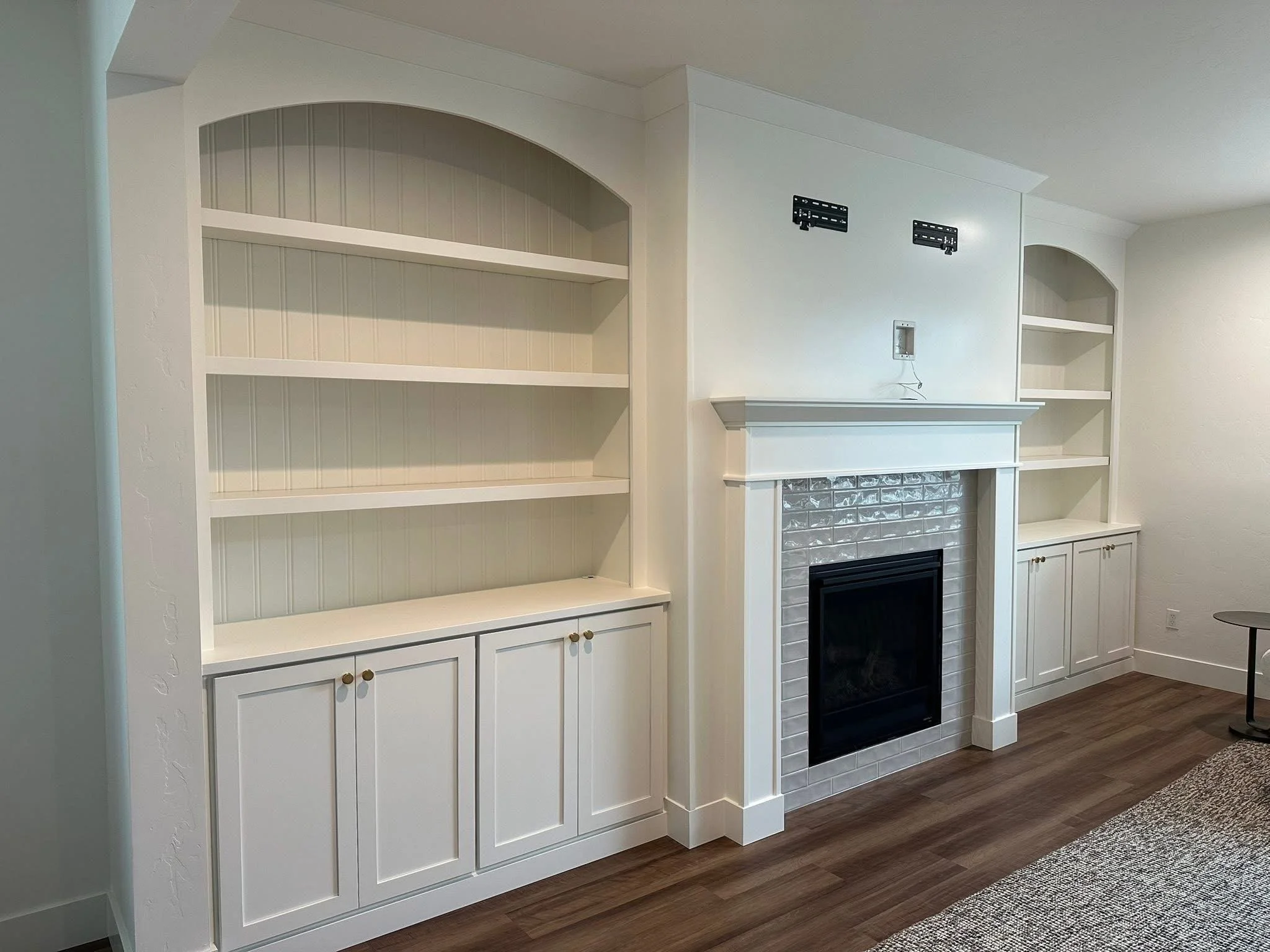 Custom entertainment center with arched built-in shelving, white cabinetry, and fireplace surround in Star, Idaho.