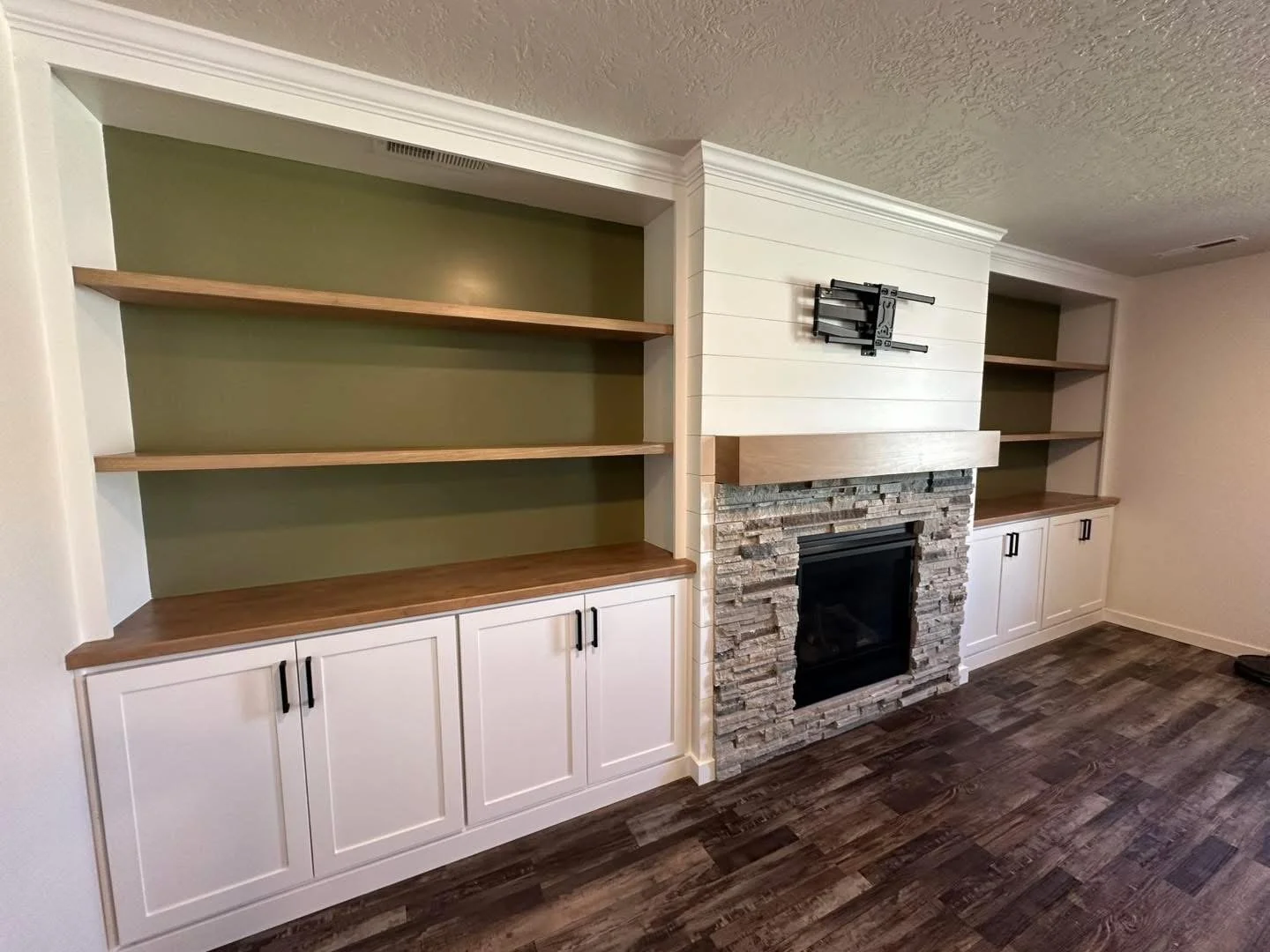 Floating wood shelves and custom cabinetry installed around a living room fireplace.
