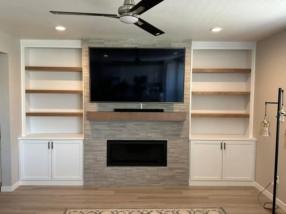 Custom fireplace built-ins with white shaker cabinets, white oak floating shelves, and a modern stone fireplace in a Meridian, Idaho home.