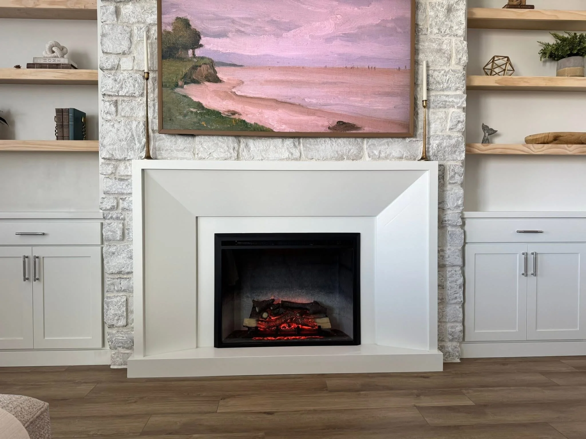 Close-up of a modern stone fireplace surround with a custom fireplace mantel and built-in cabinetry in Caldwell, Idaho.