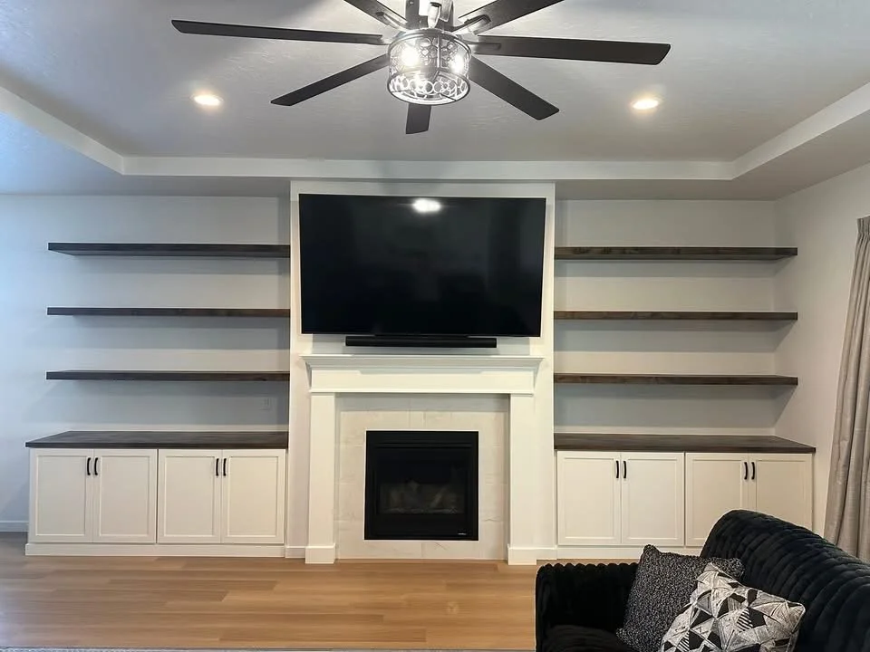 Custom built-in entertainment center with floating wood shelves, white shaker cabinets, and a modern fireplace in Star, Idaho.
