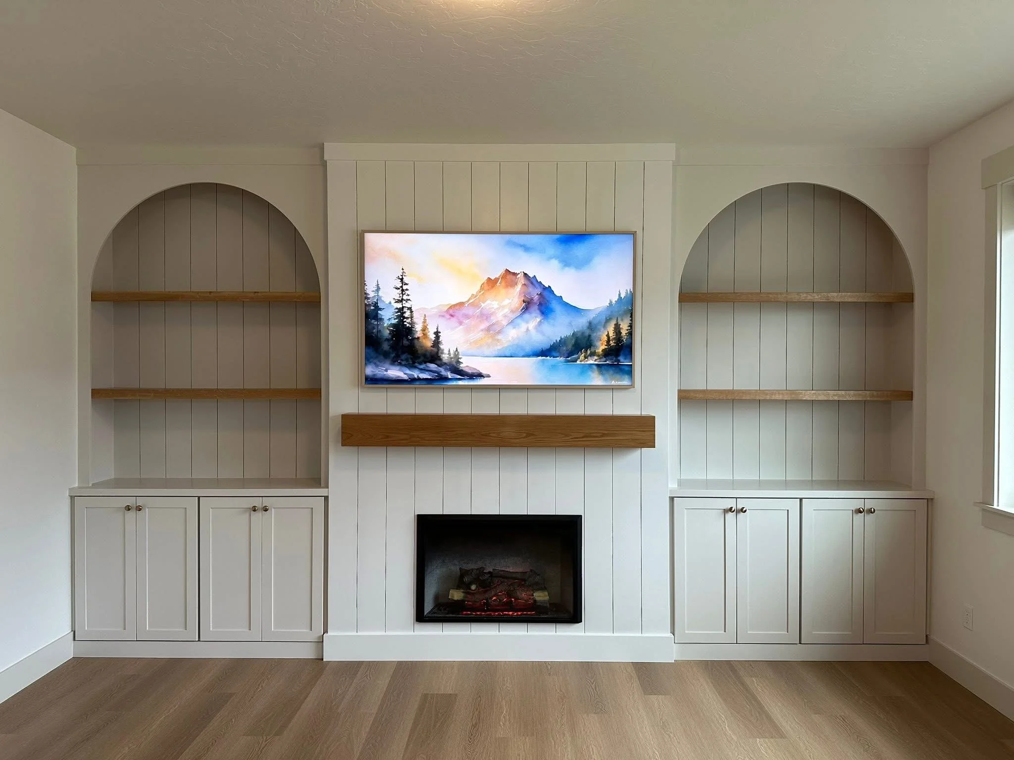 Custom entertainment center featuring arched built-in shelving, lower cabinets, and a modern fireplace in Meridian, Idaho.