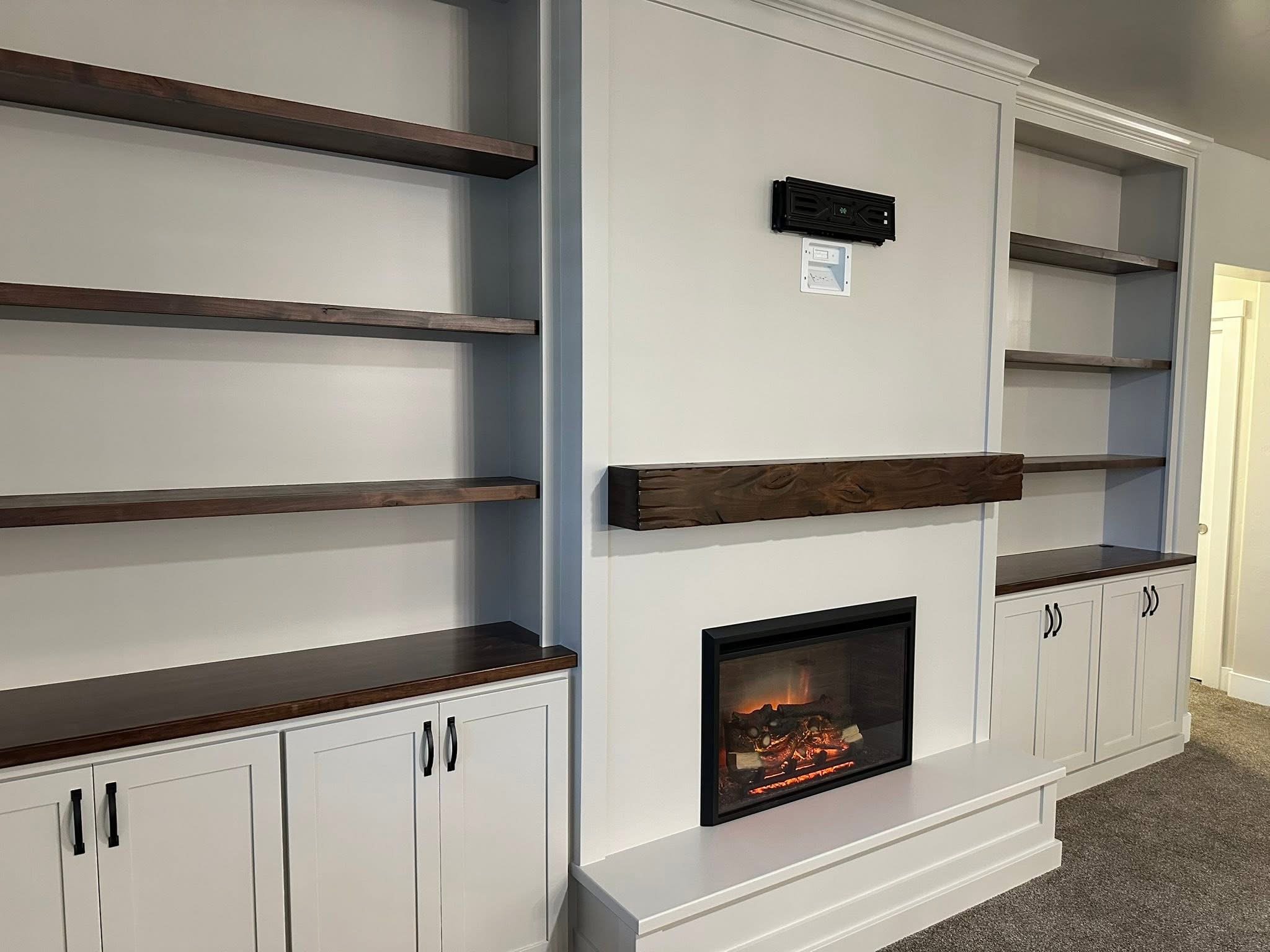 Custom fireplace mantel with painted built-ins, floating wood shelves, and white shaker cabinets in Meridian, Idaho.