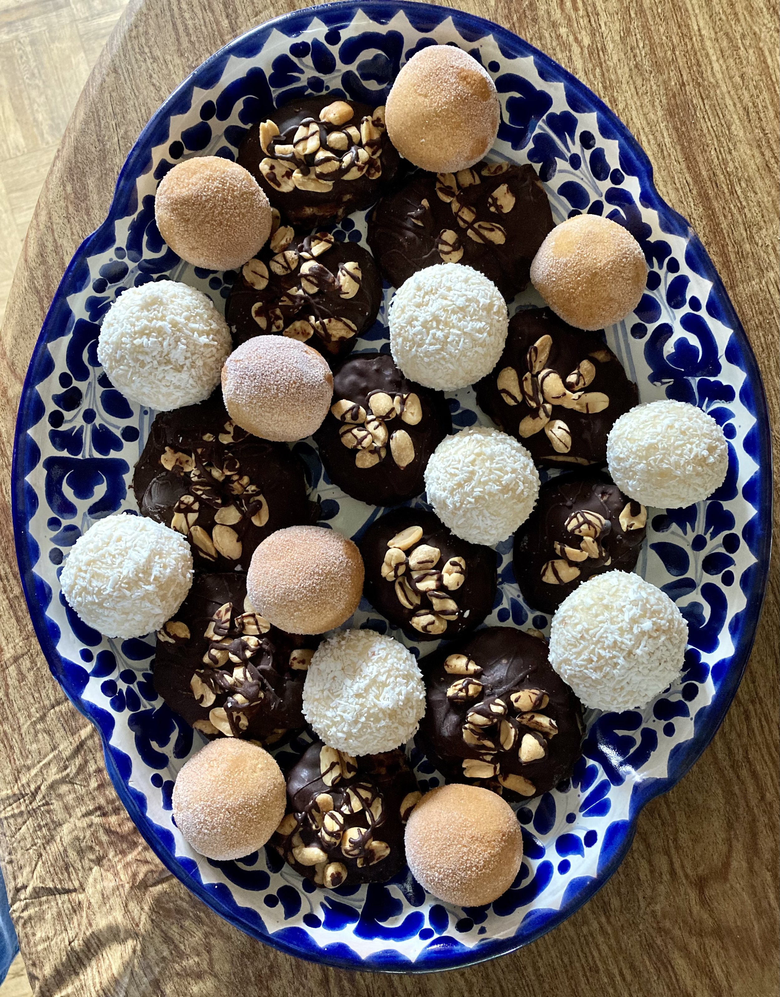 Assorted chocolate truffles with nuts and coconut on blue and white ceramic plate.