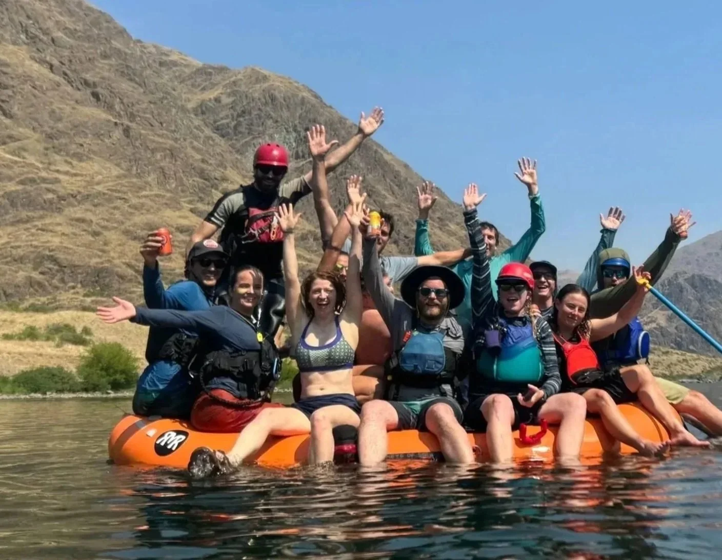 A group of adventurers celebrating successfully navigating white water rapids.
