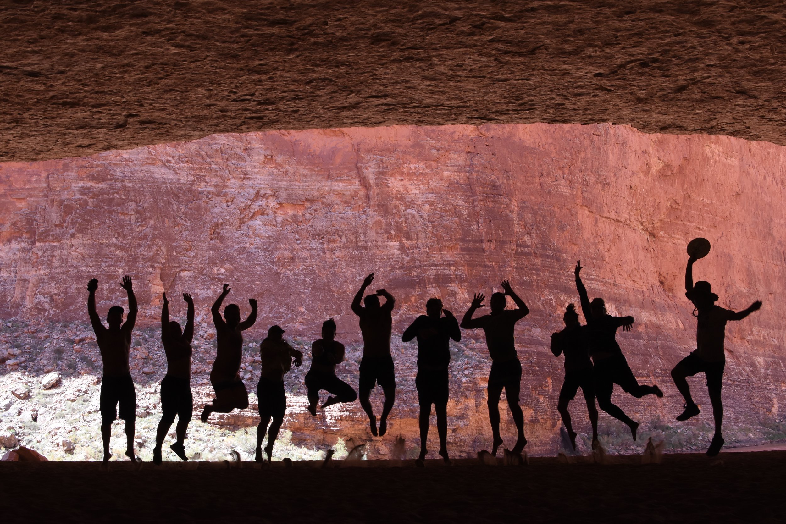 A group of friends silhouetted in a canyon.