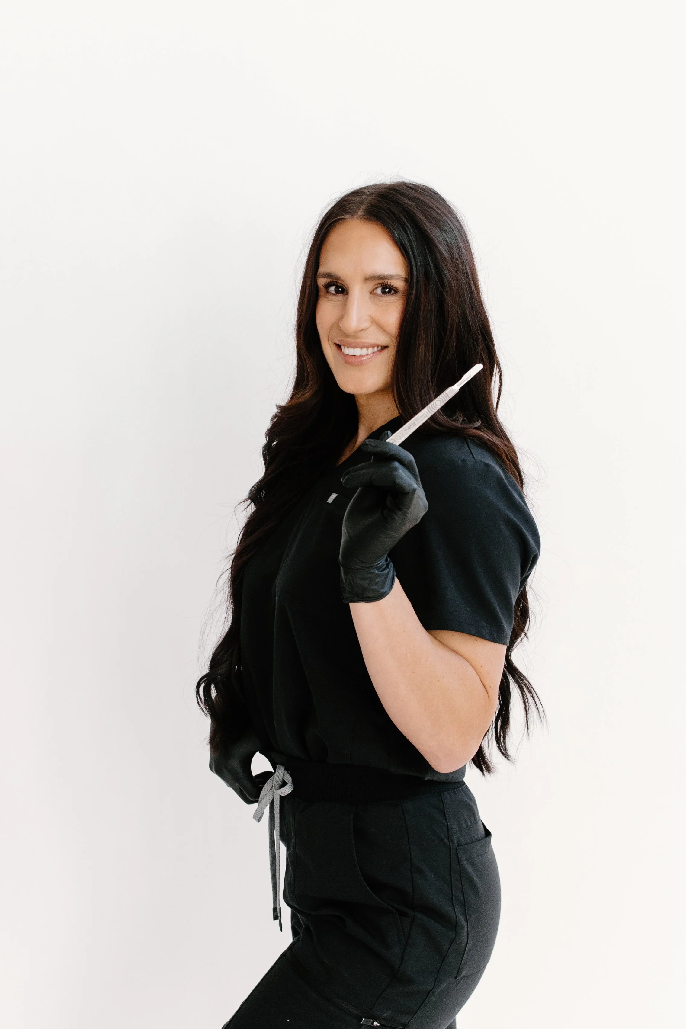 Licensed Esthetician and Owner of Allure Aesthetics and Beauty Co. in Oregon, Illinois, holding a Microchanneling (similar to Microneedling) tool for clients looking for corrective skincare and facial treatments.