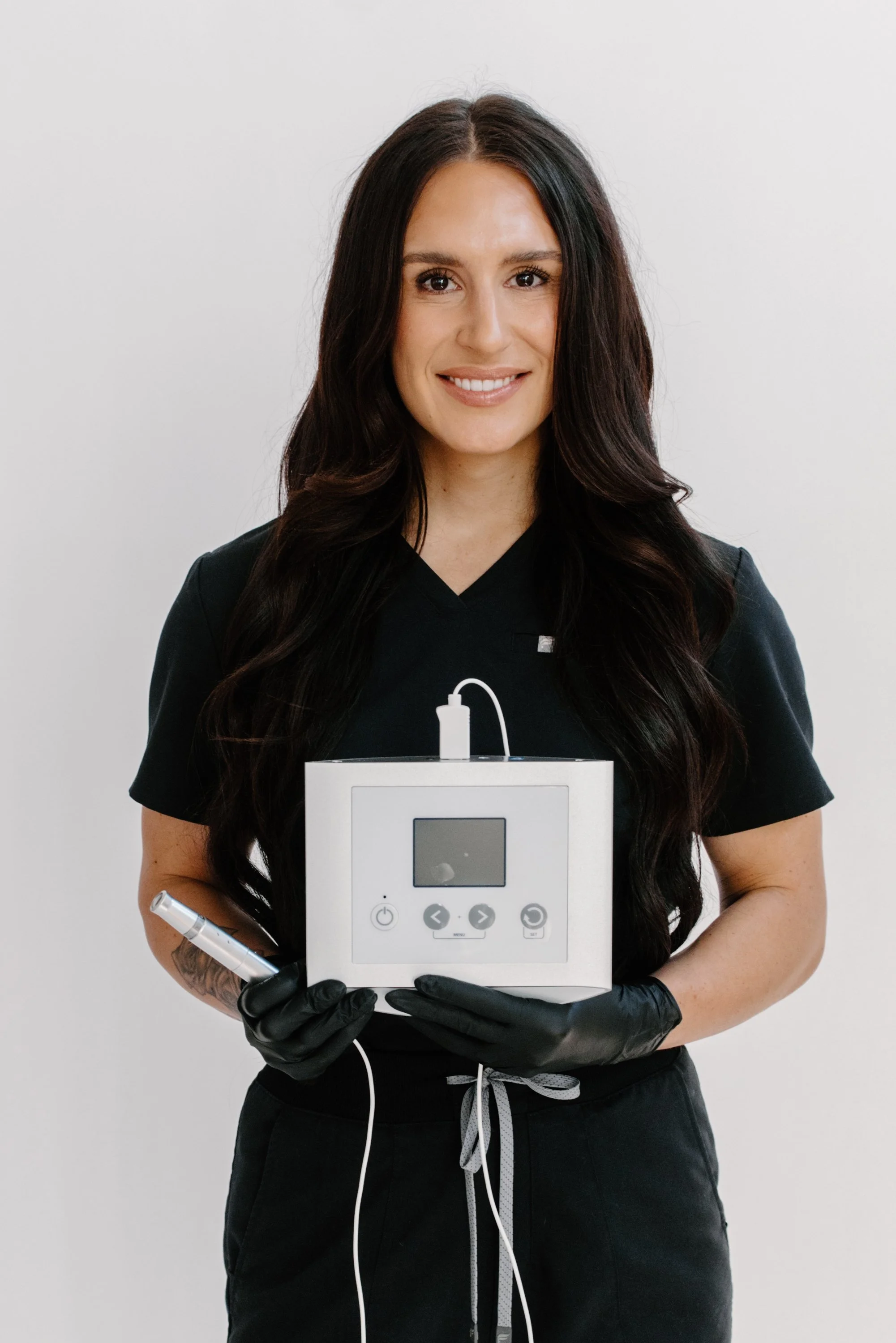 Licensed Esthetician and Owner of Allure Aesthetics and Beauty Co. in Oregon, Illinois, holding a Microchanneling (similar to Microneedling) tool for clients looking for corrective skincare and facial treatments.