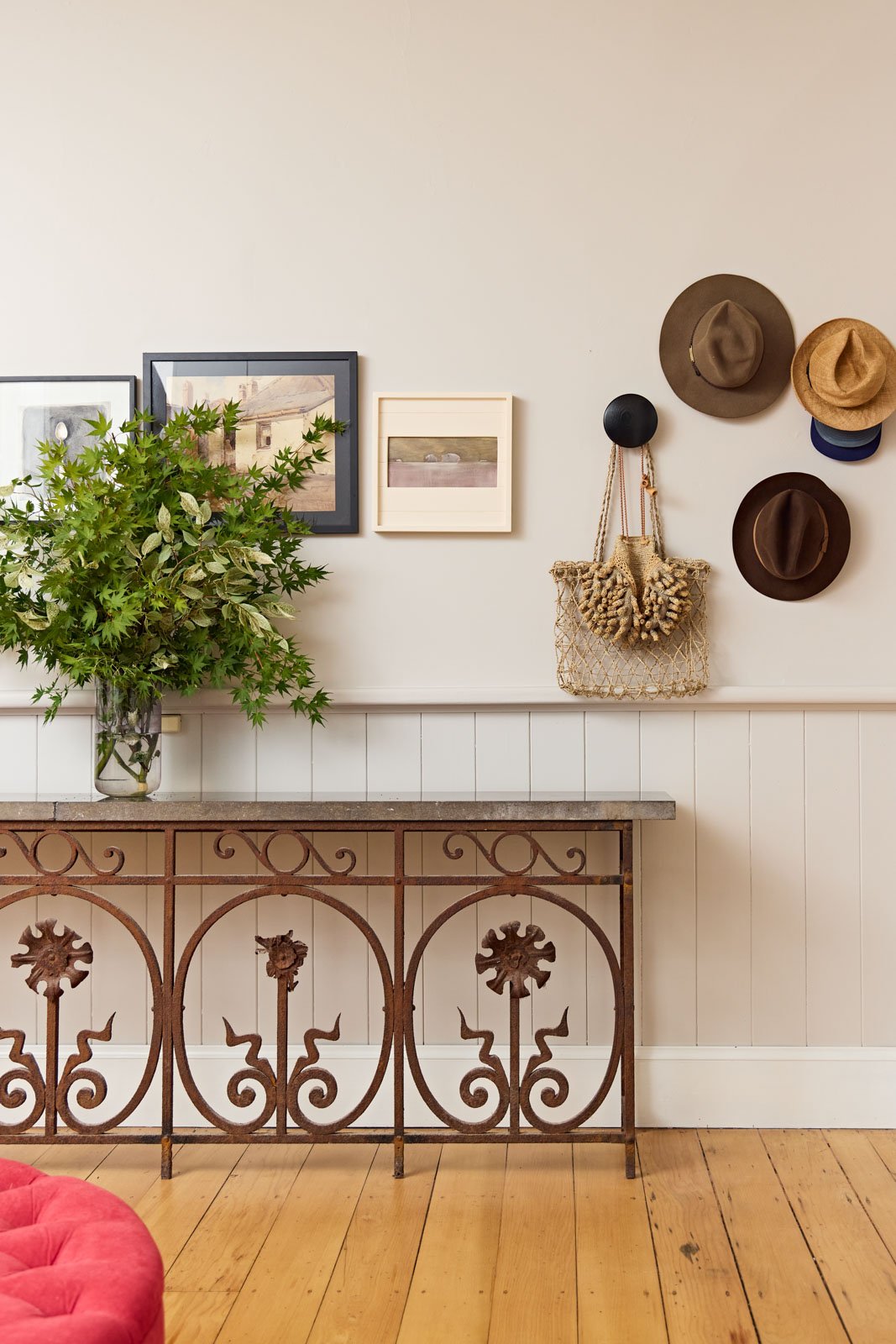 Entryway featuring antique table, hat hooks and artwork exclusively by female artists