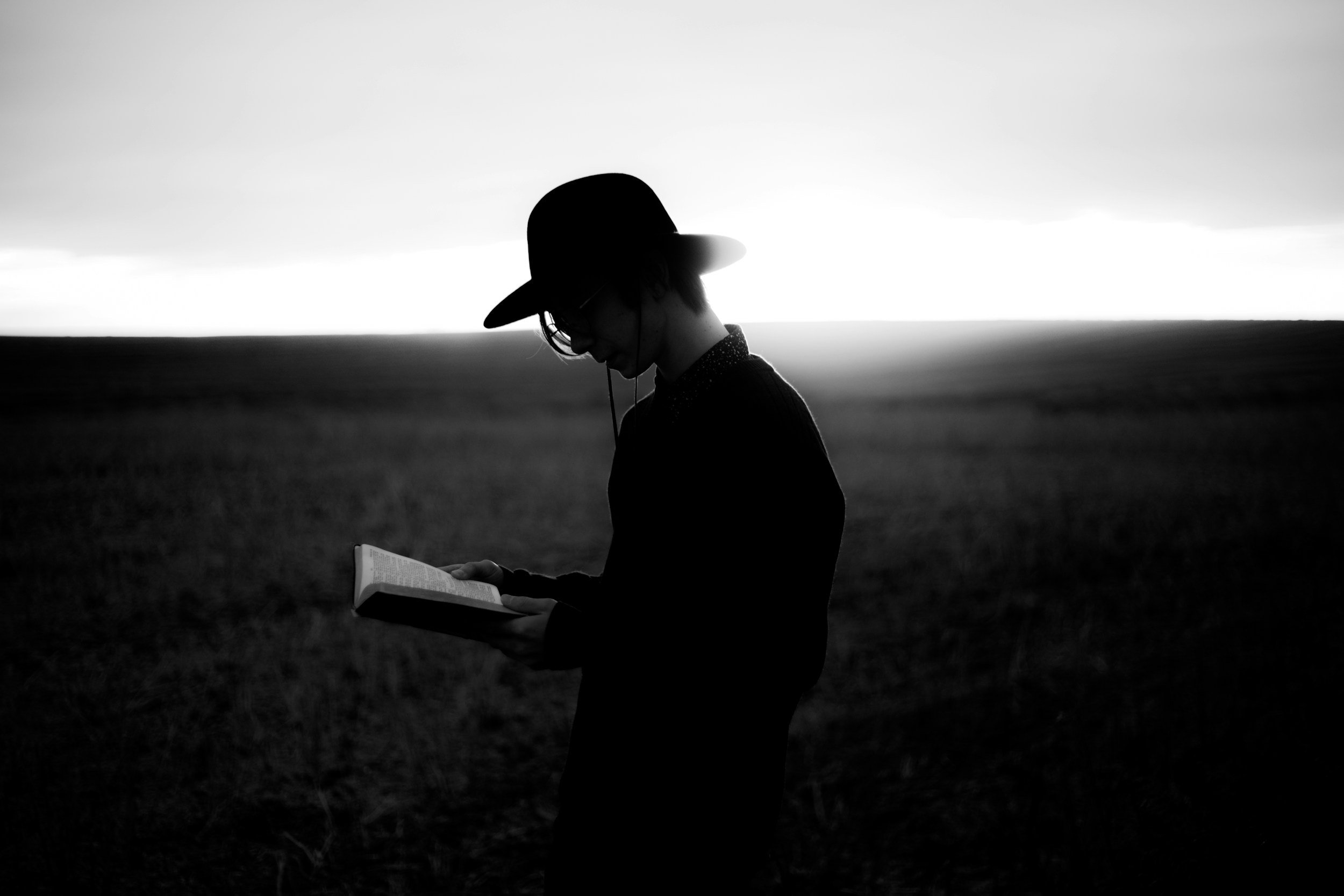 black and white image of man reading field notes in pasture