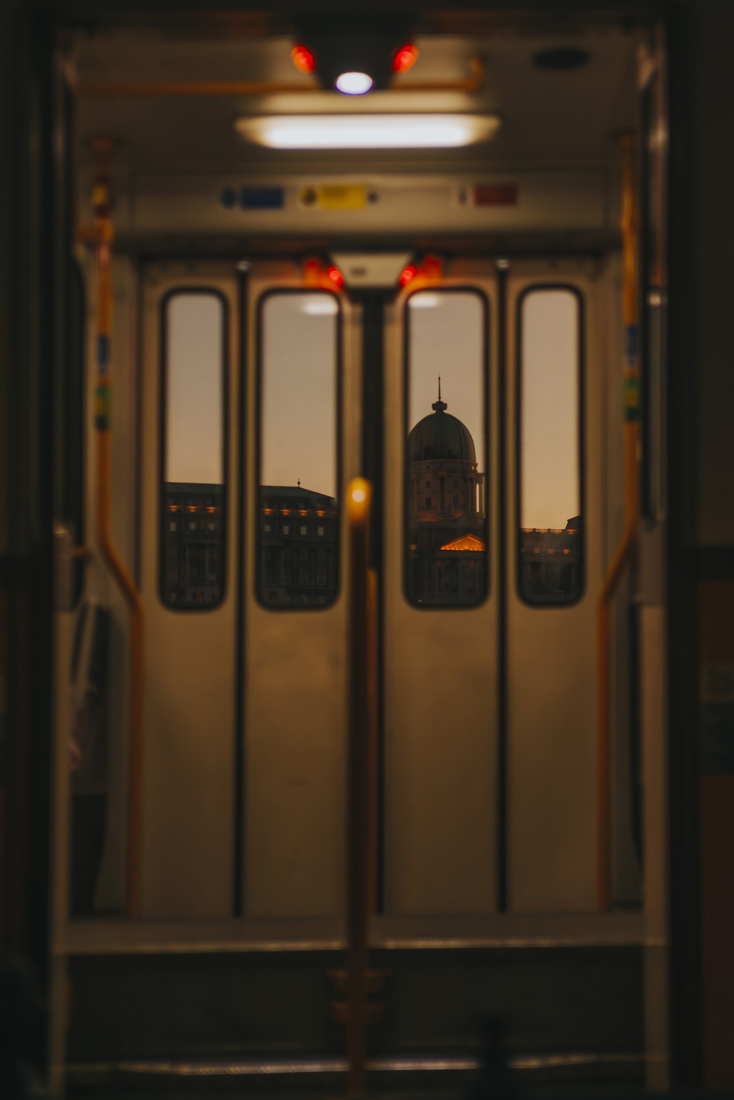 View of a city building with a dome through the doors of a tram at sunset.