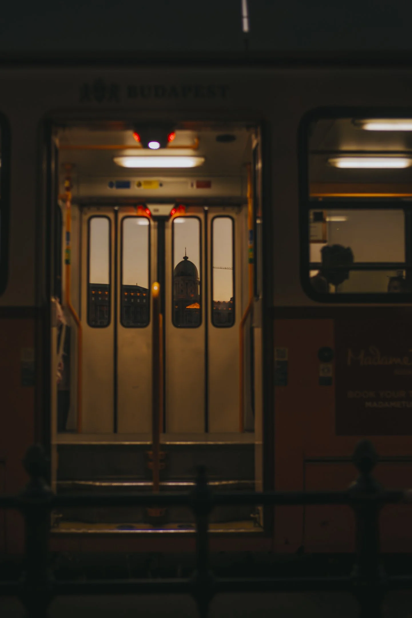 Photo of a subway train door with a view of a historic building with a dome through the open doors, during sunset or dusk.