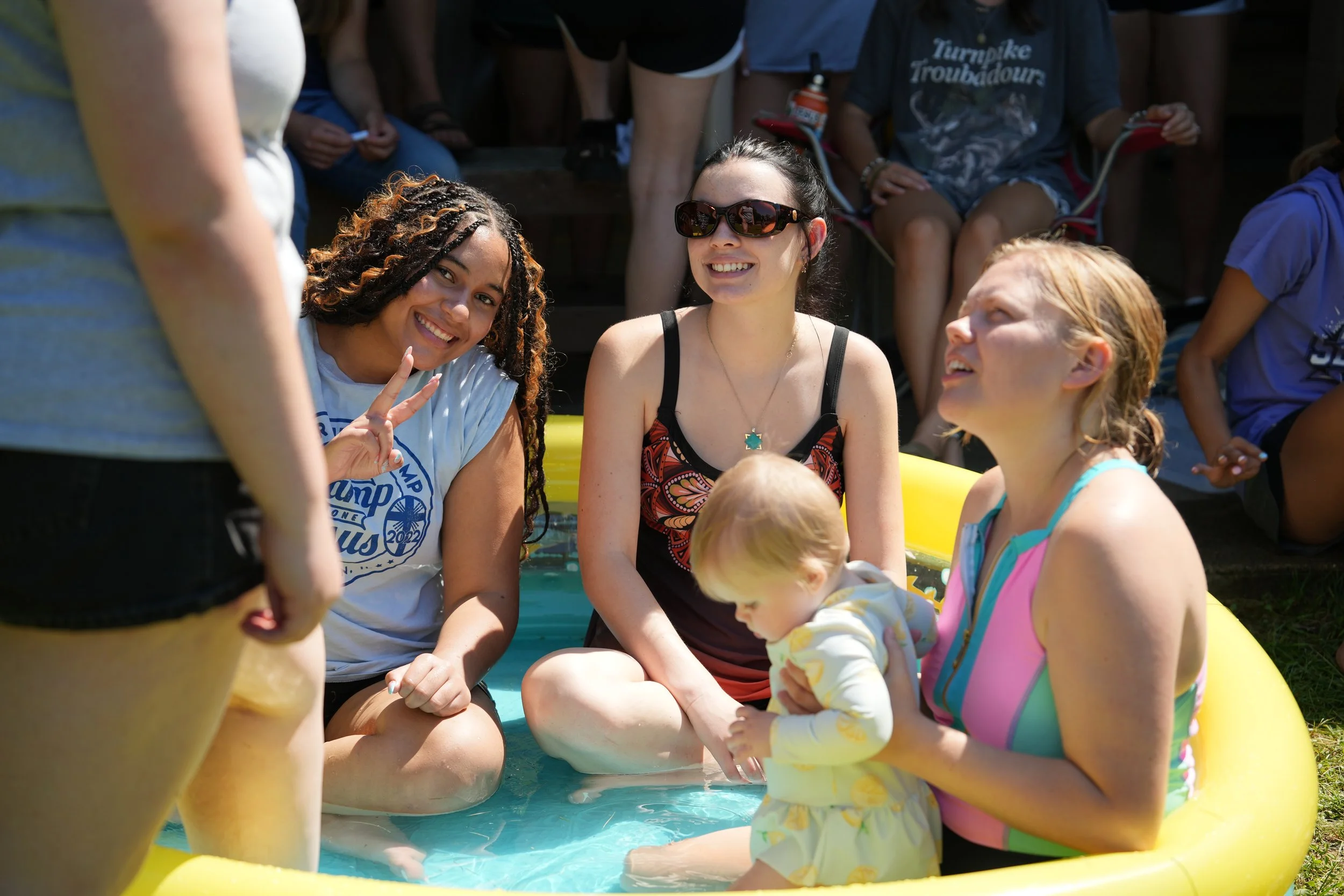 Group of friends enjoying a summer day in a small pool, smiling and talking to each other.