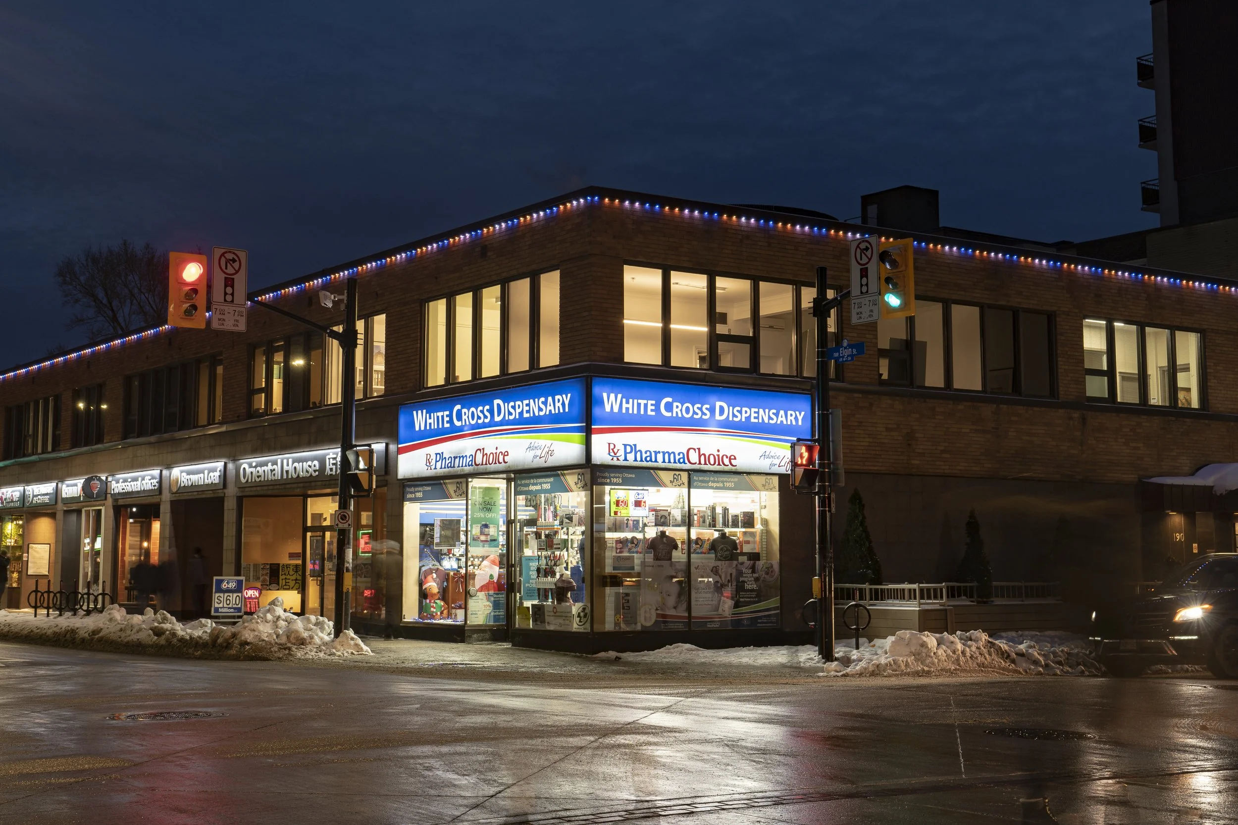 A multi-story house decorated with white and blue holiday lights at night.