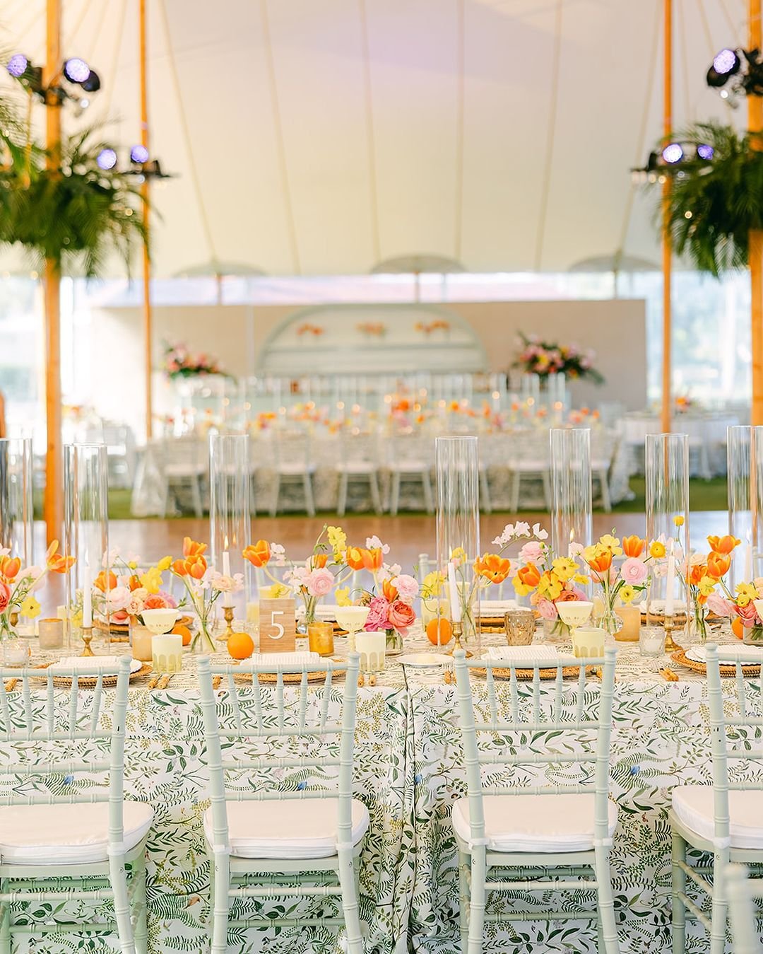 Bright, beautiful, and full of charm! This vibrant table setup under a Sperry Tent is the perfect blend of natural elegance and bold colors. The lush floral arrangements, intricate tablecloth patterns, and warm candlelight create a magical atmosphere