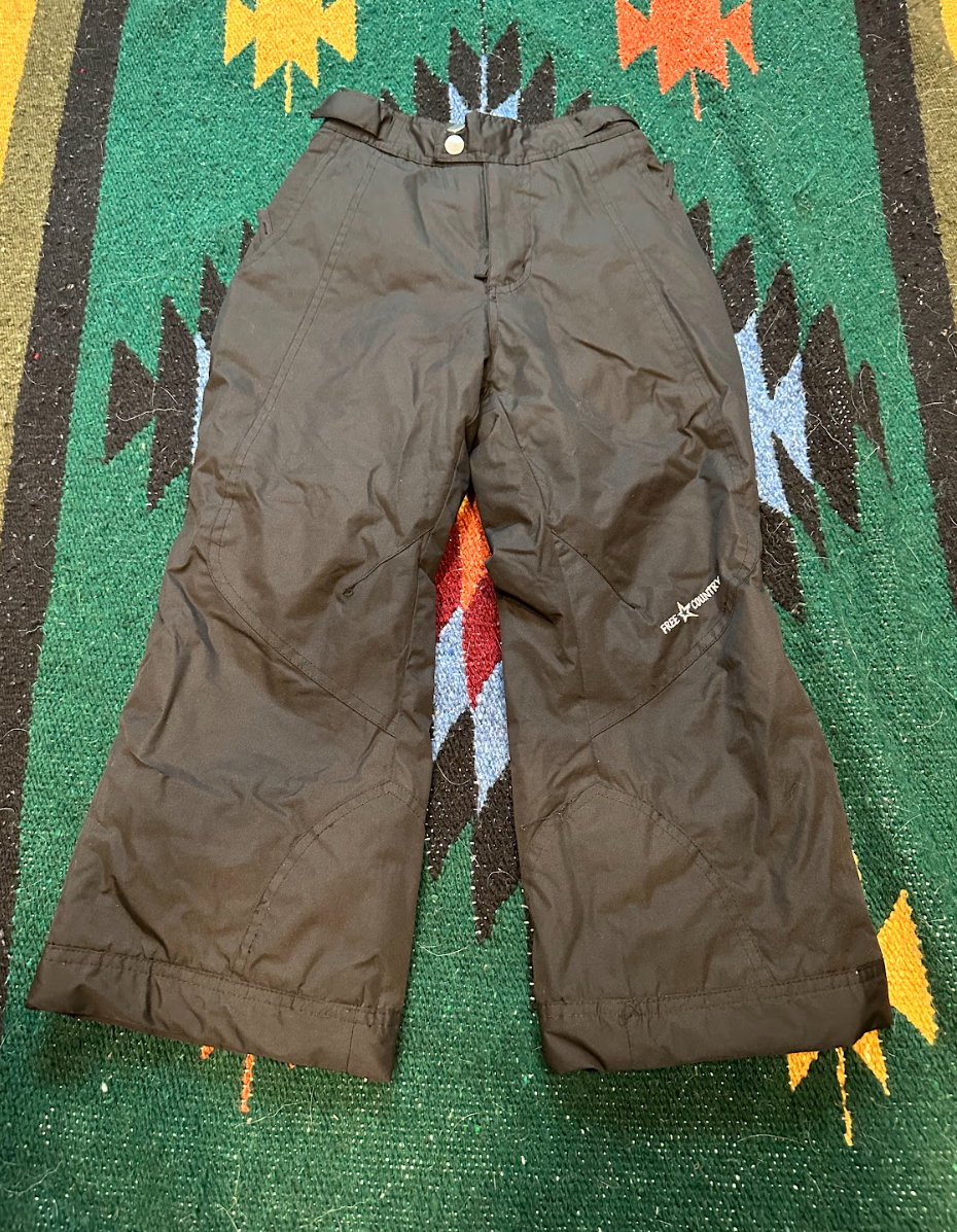 Brown snowboarding pants on a colorful geometric-patterned rug.
