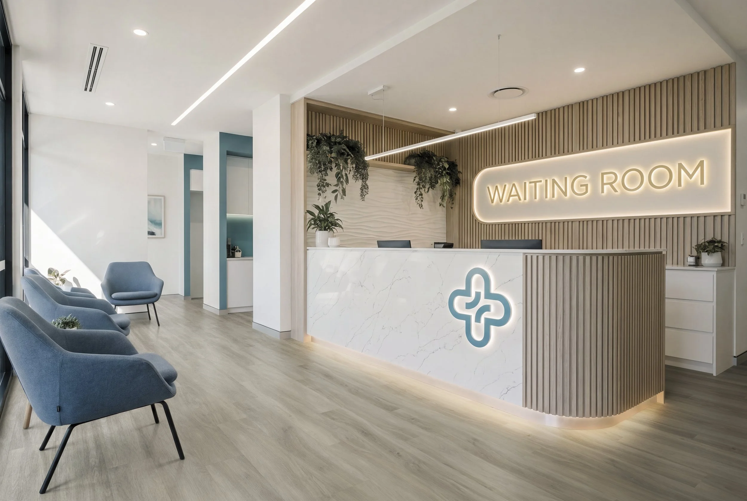 Commercial reception CGI with medium light wood LVT plank flooring, digitally laid for realistic interior flooring visualisation with grey chairs arranged along a light wood floor, white walls, and a reception desk with a illuminated sign saying 'Wai