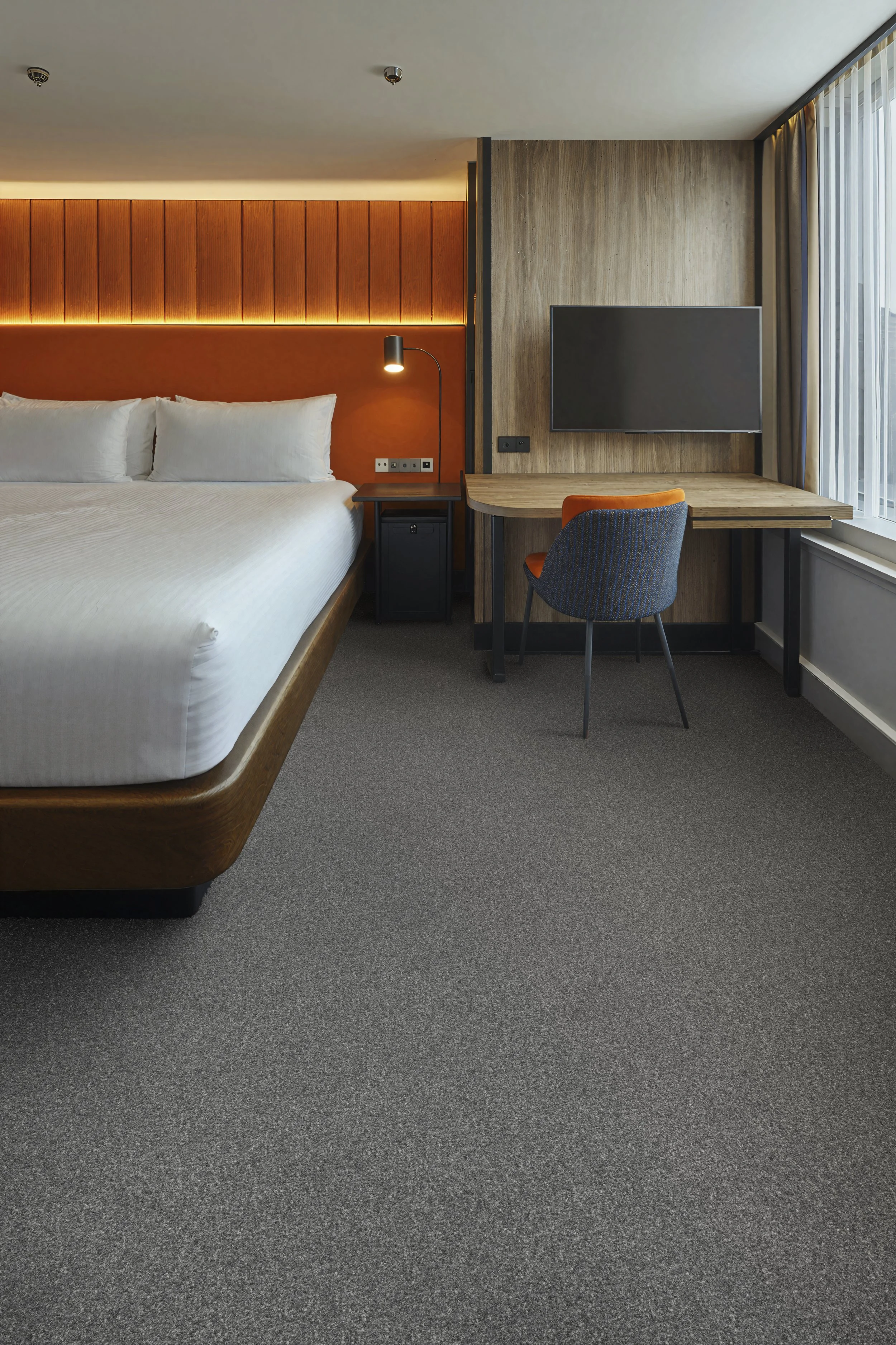 Grey commercial carpet has been digitally laid into this contemporary hotel bedroom to demonstrate how soft flooring enhances comfort and complements modern hospitality interiors. The realistic CGI showcases a stylish guest room with crisp white bedd