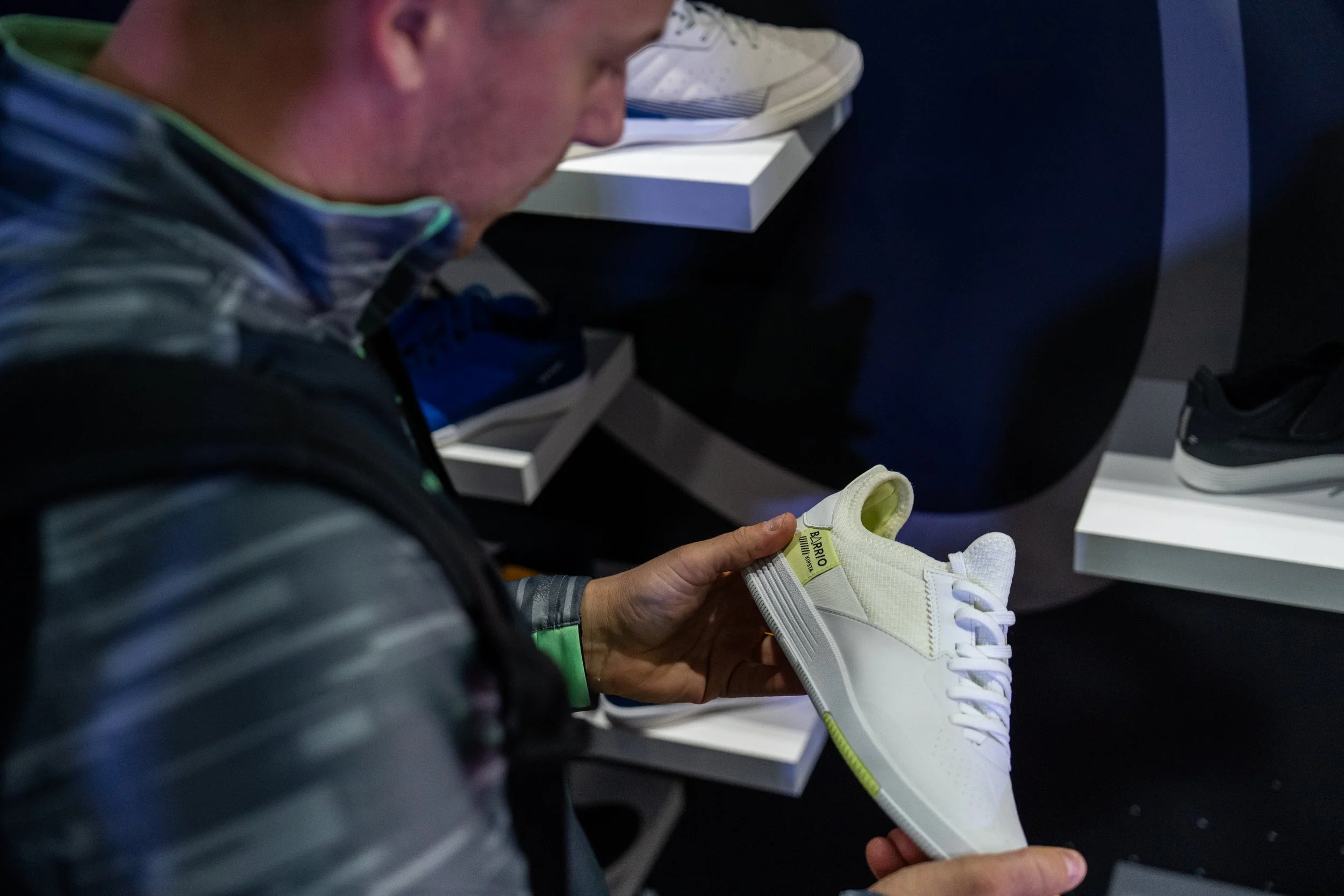 Un homme regarde une chaussure blanche lors d'une exposition de sneakers.