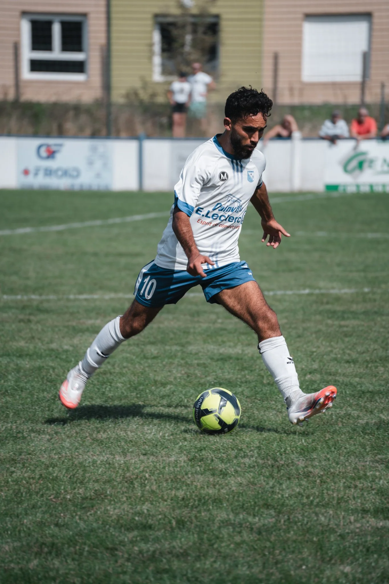 Un joueur de football en train de courir avec un ballon sur un terrain en herbe.