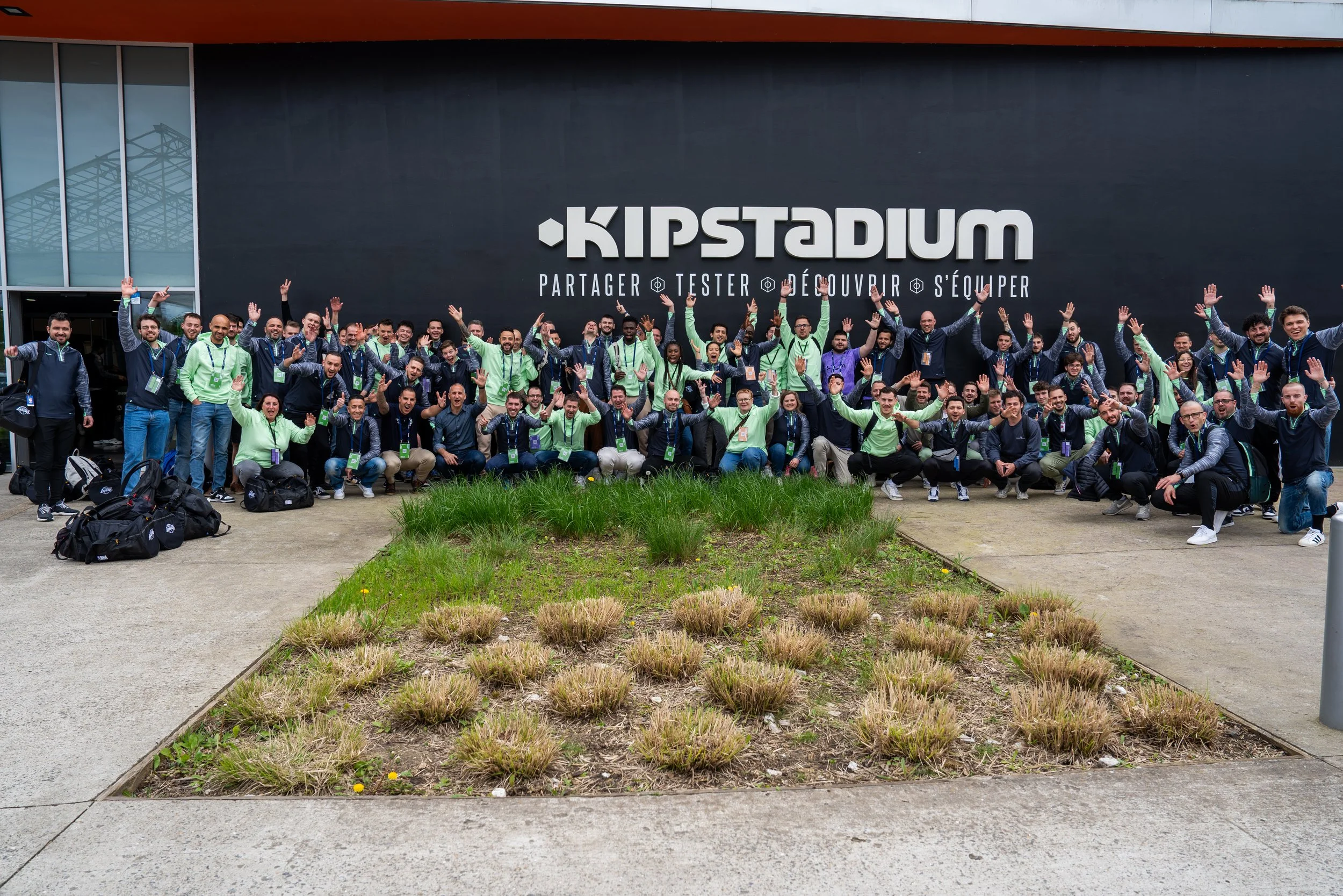 Groupe de personnes posant devant le bâtiment Kipstadium, avec le slogan partager, tester, découvrir, s'équiper