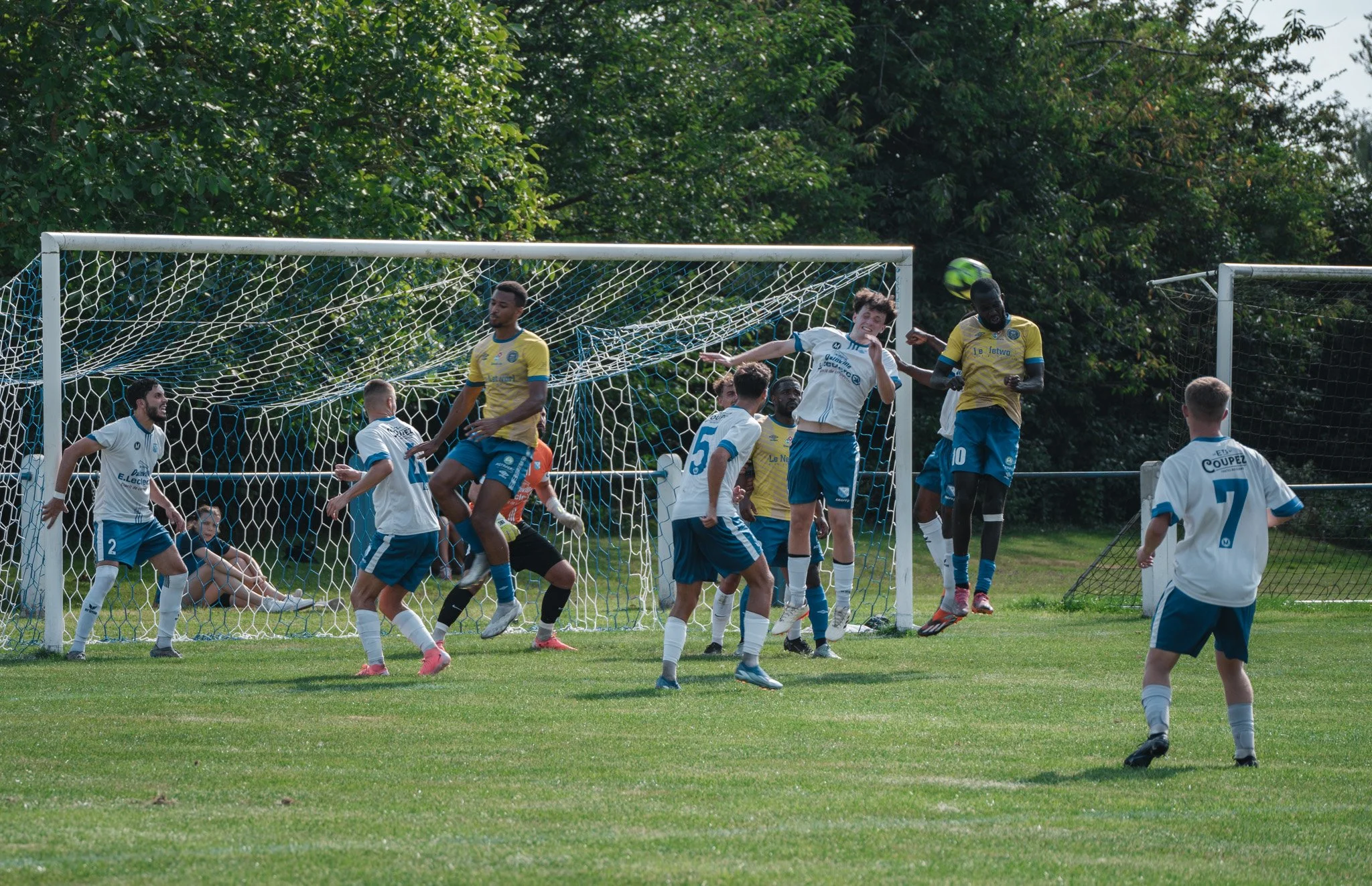 Match de football en cours avec des joueurs essayant de marquer un but, bâche dans la zone de but.
