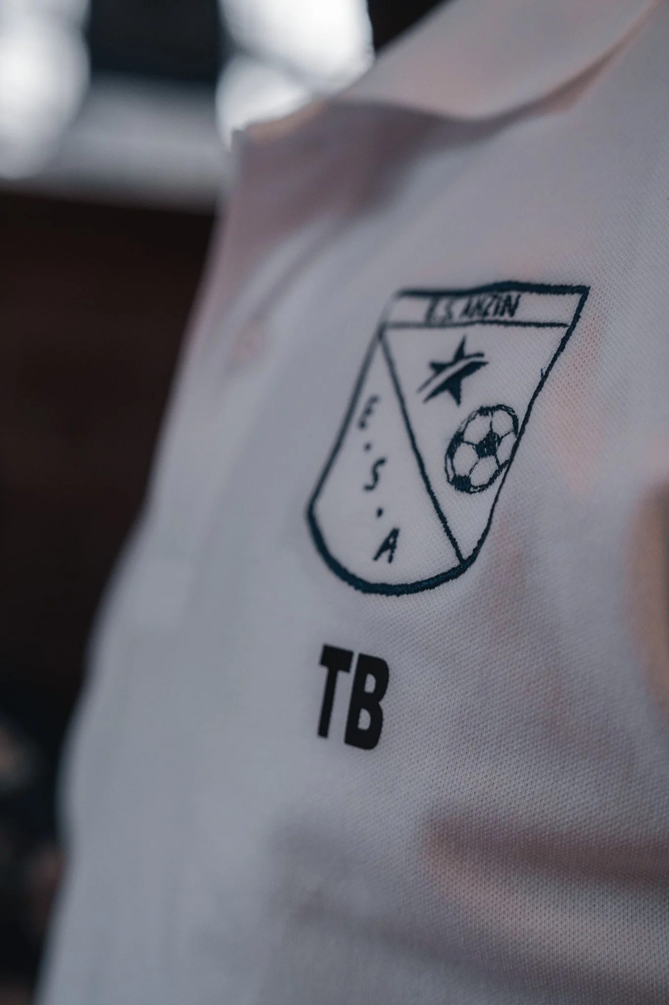 Le logo de l'équipe de football de la Tunisie sur un maillot blanc, avec les initiales T.B.