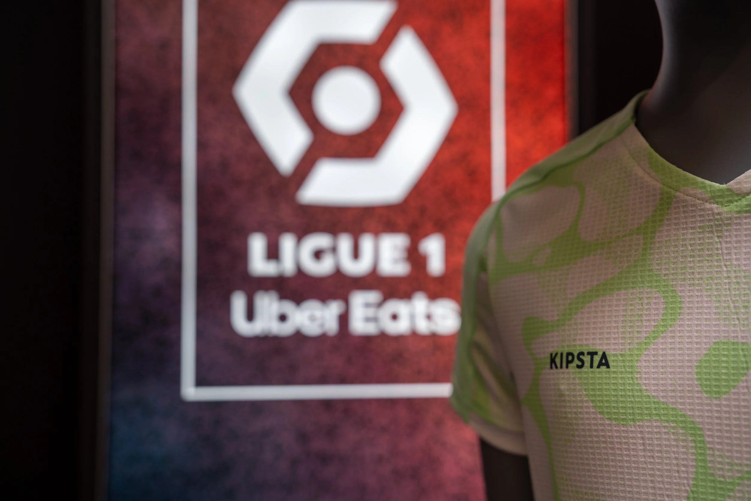 Mannequin portant un maillot avec le nom 'KIPSTA' devant un panneau avec le logo de la Ligue 1 Uber Eats.