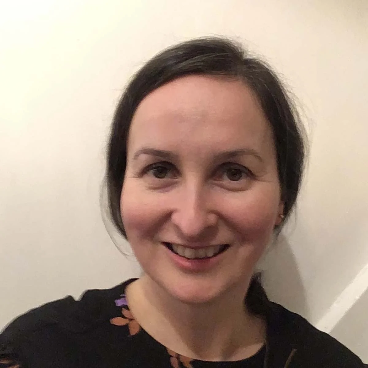 Linda is a white woman with long dark hair that has been tied back. She is wearing a black top.