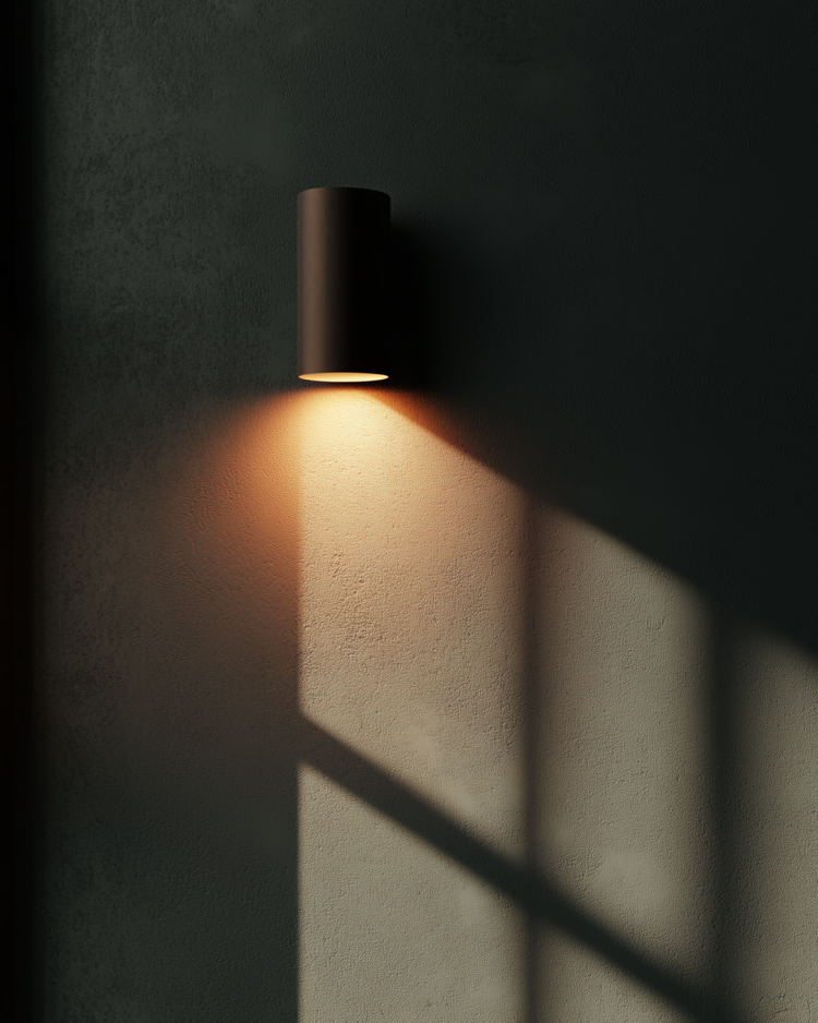 Wall-mounted black cylindrical light fixture casting a warm glow and shadow on a textured wall.