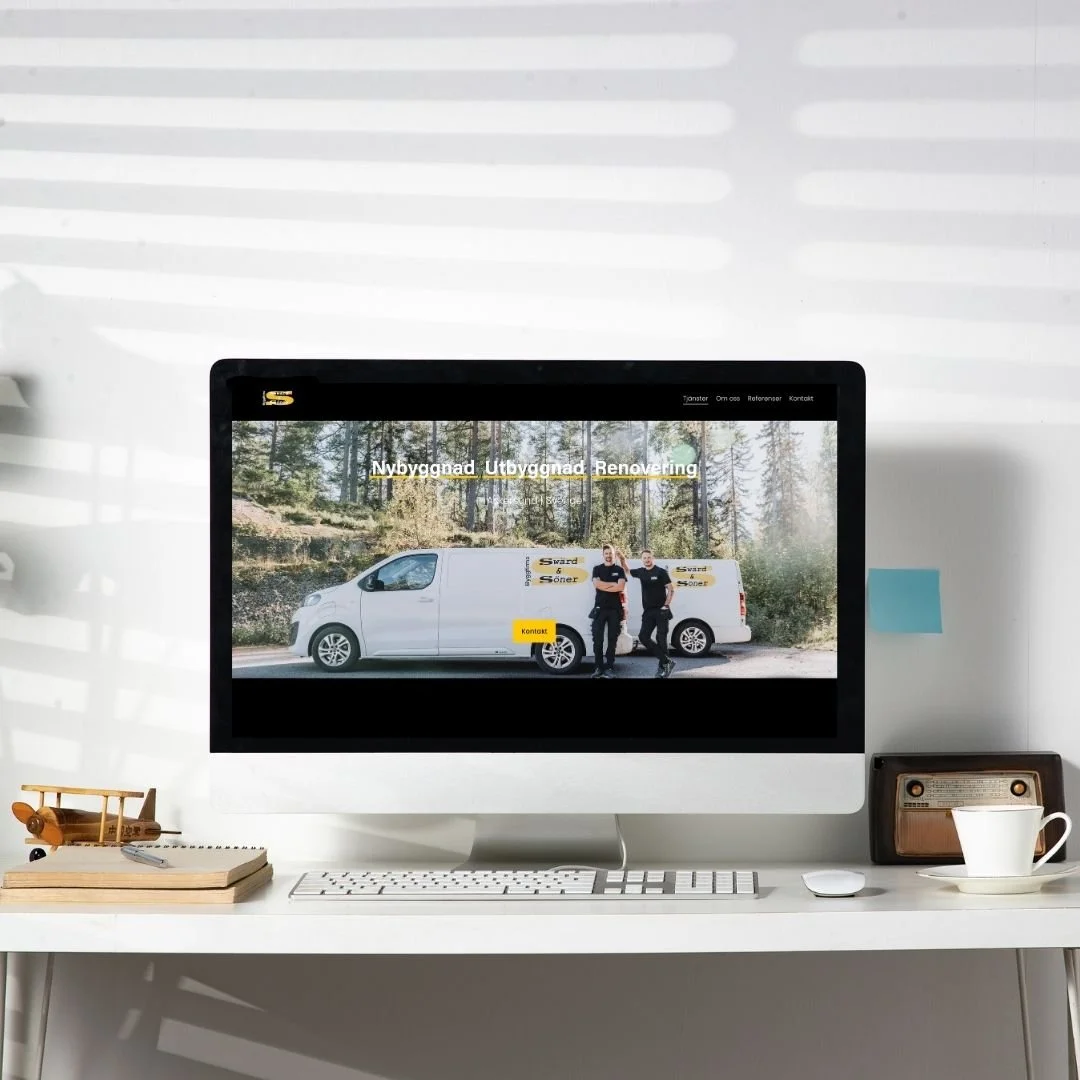 En skärm på ett skrivbord visar en webbsida byggd och uppsatt av Isabel Azcárate Din Marketing Coach och Johanna Egemar, företagsfotograf och egenföre för ett bygg- och renoveringsföretag, med två personer som står bredvid en vit bil i en skogsmiljö.