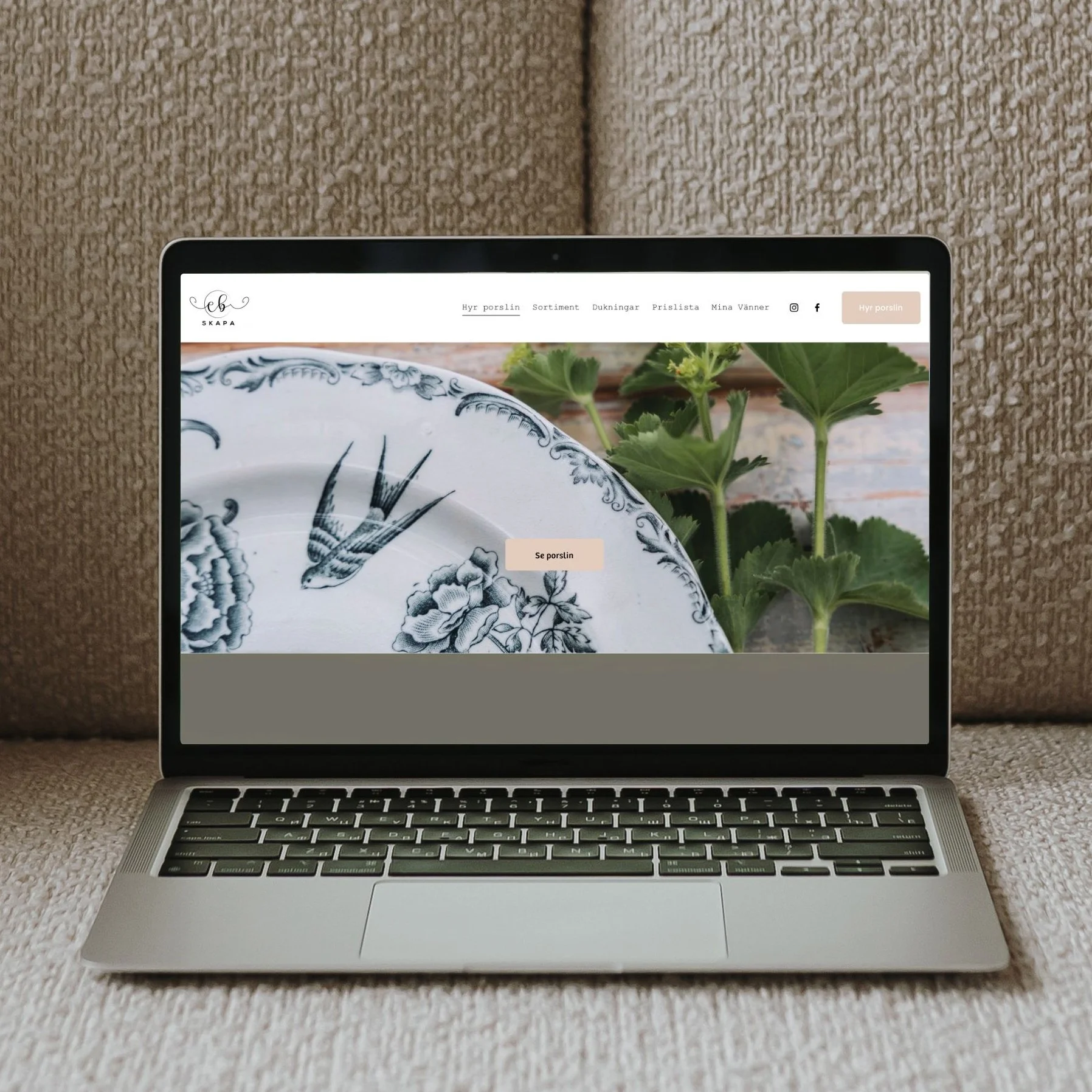 En MacBook-laptop placerad på en beige matta, som visar en webbsida för en porslinsuthyrning med knappen "Se porslin" i mitten.