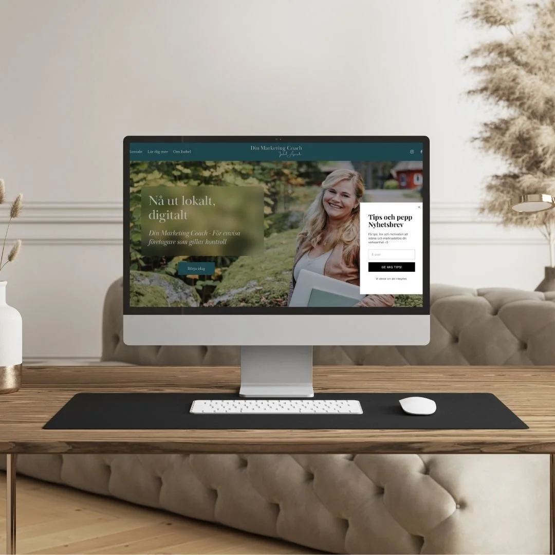 Dator på ett skrivbord med en webbsida för en marknadsföringscoach, en vit skrivbordsstol, ett vaser med växter och en bäddsoffa i bakgrunden uppsatt av Isabel Azcárate Din Marketing Coach och Johanna Egemar, företagsfotograf.