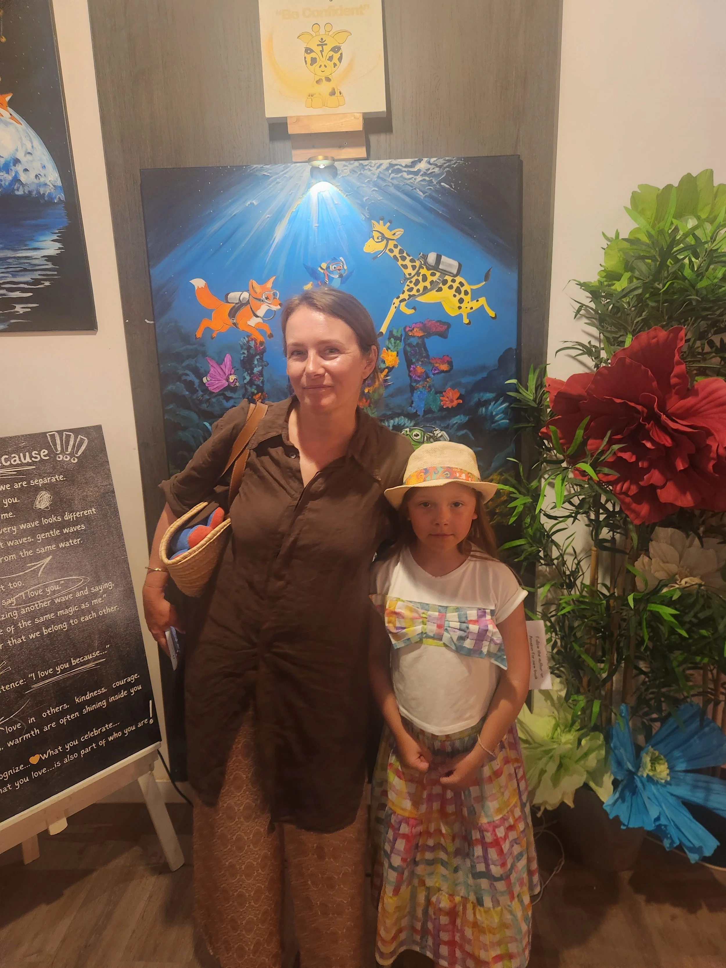 A woman and a young girl are standing in front of the I love you because... art exhibition.