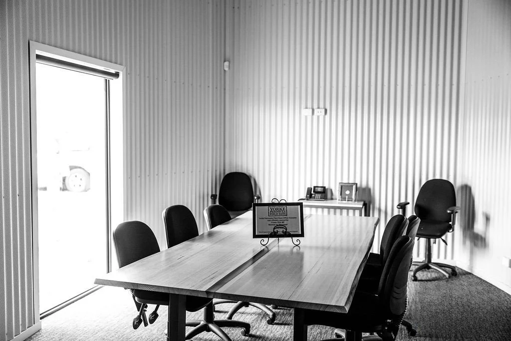 Boardroom at the Paskeville Field Days facility, with a long timber table and office chairs against corrugated  walls