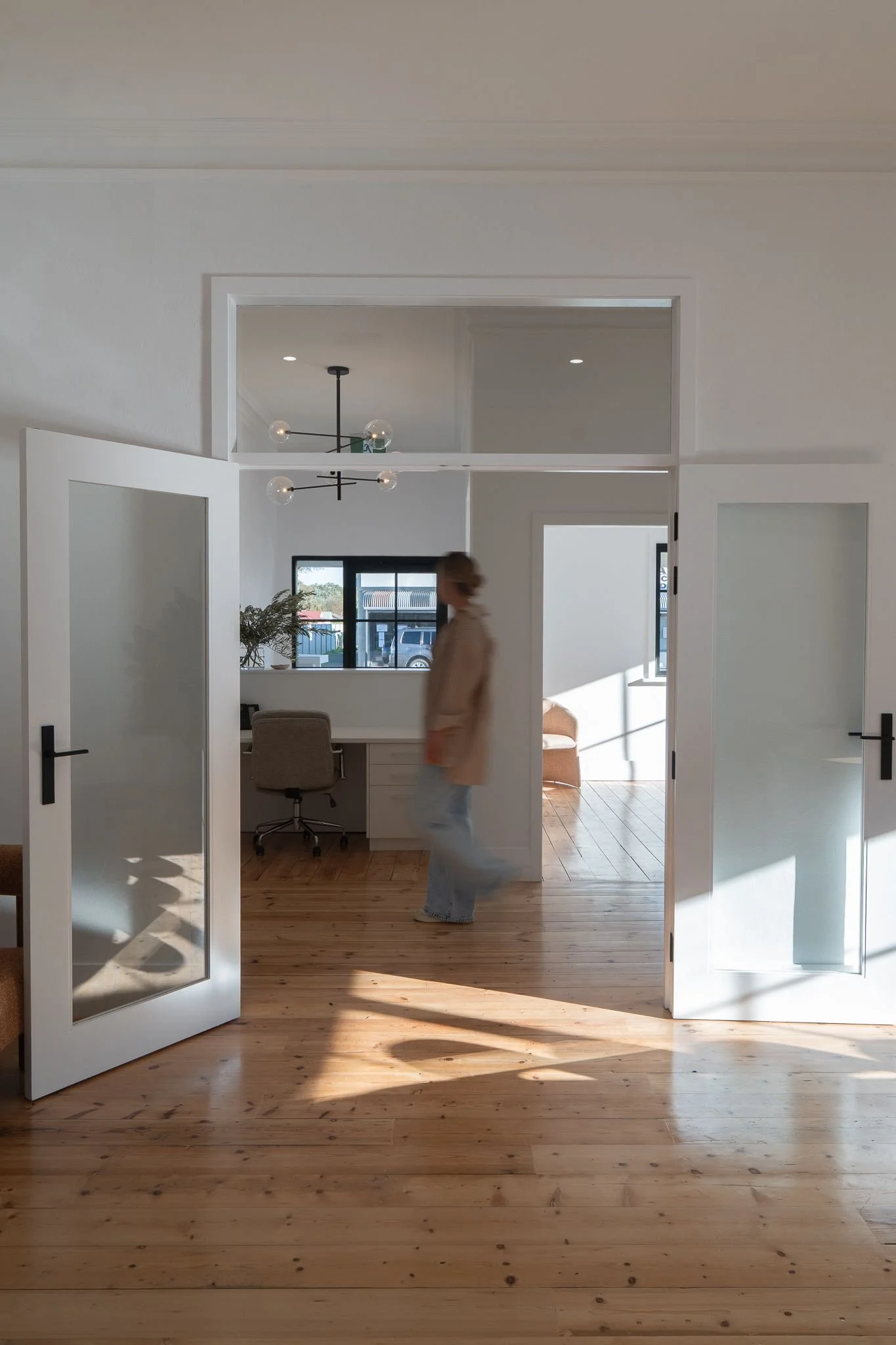 blurred image of woman walking past a open glass doorframe, in modern renovated office