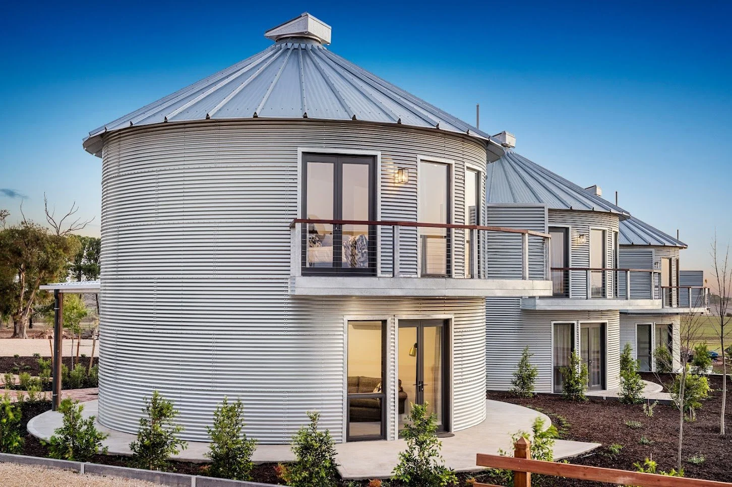 Newly constructed double storey silo accommodation in freeling, wrapped with corrugated iron and landscaped greenery, shot at sunset