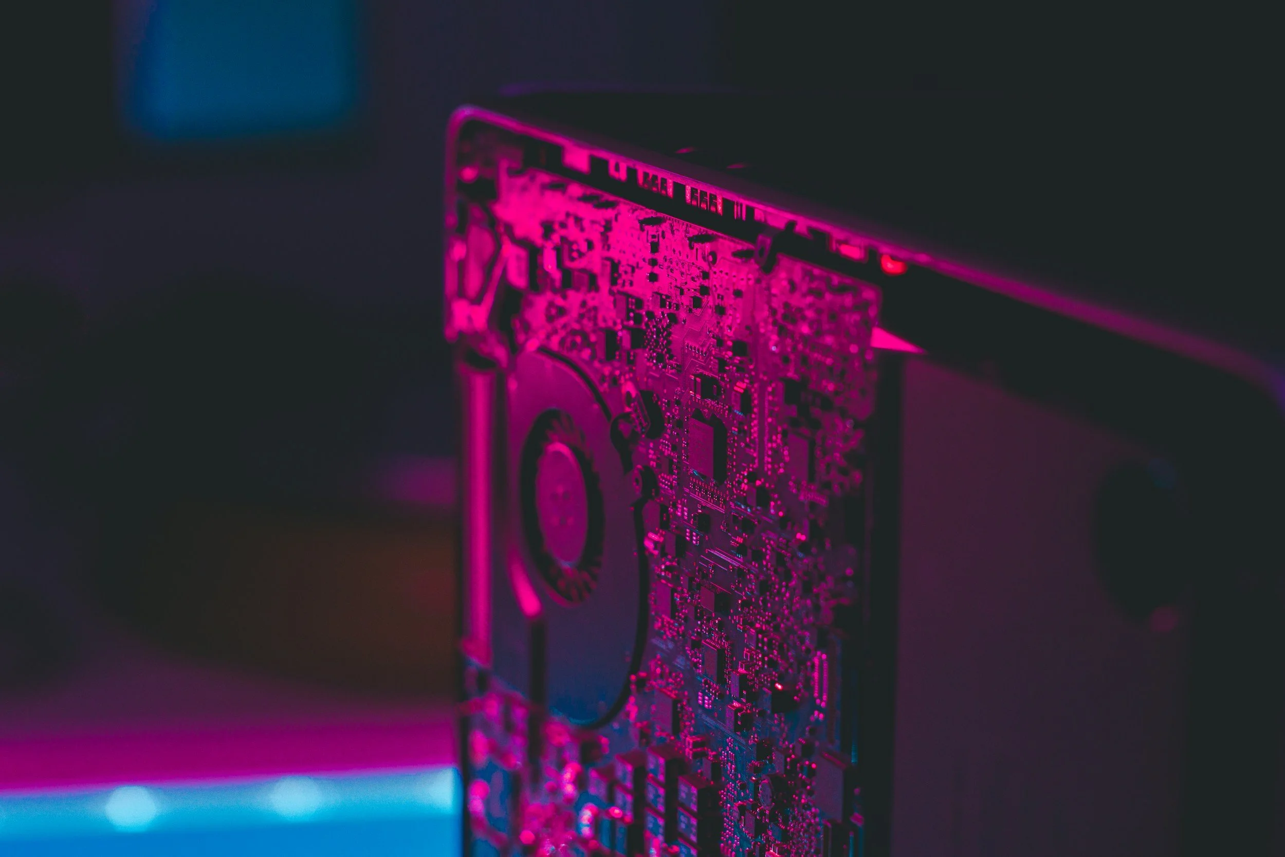 Close-up of a computer circuit board illuminated with pink and purple lighting.