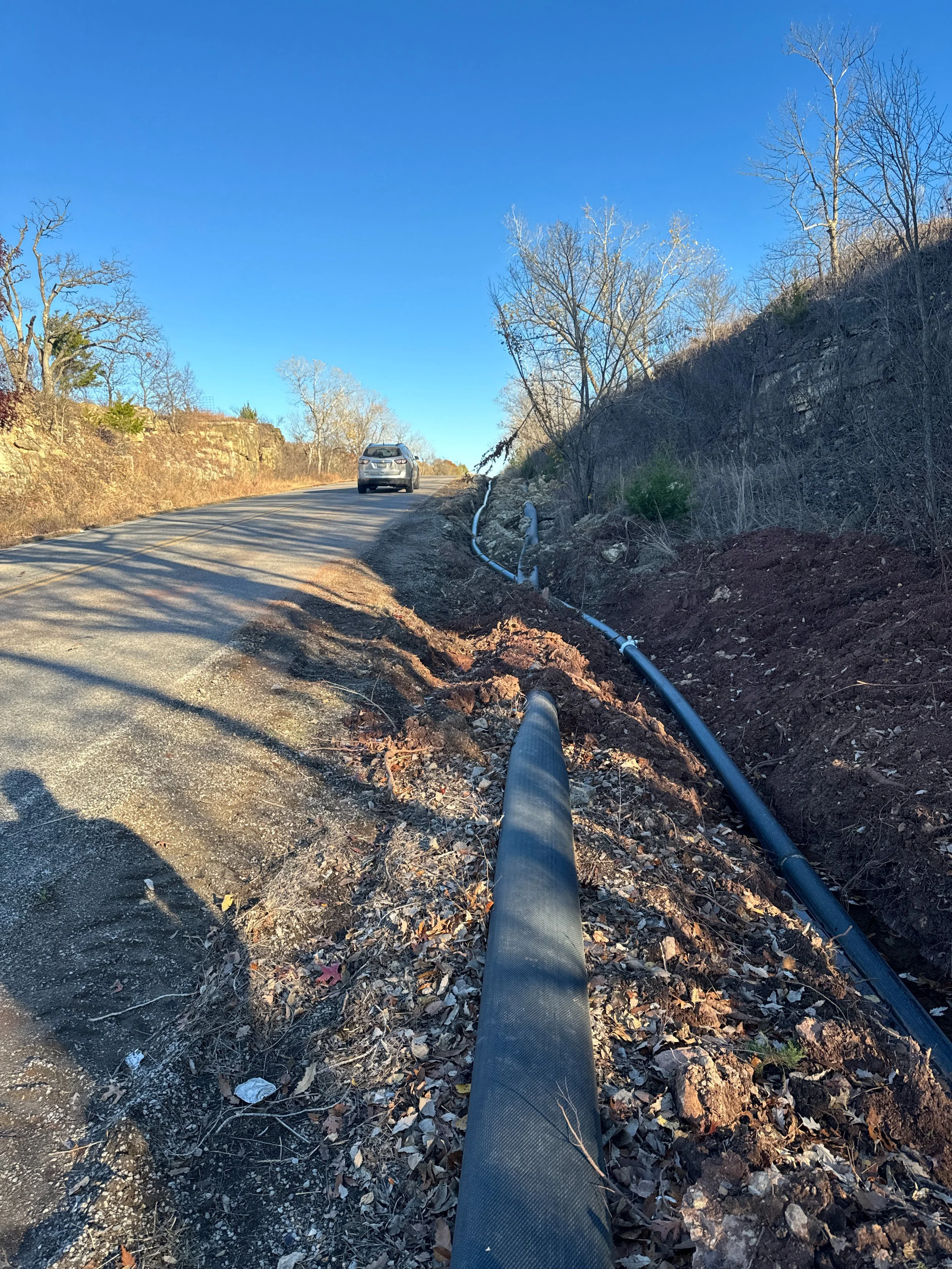 Roadside construction work with large pipe and car on a rural road