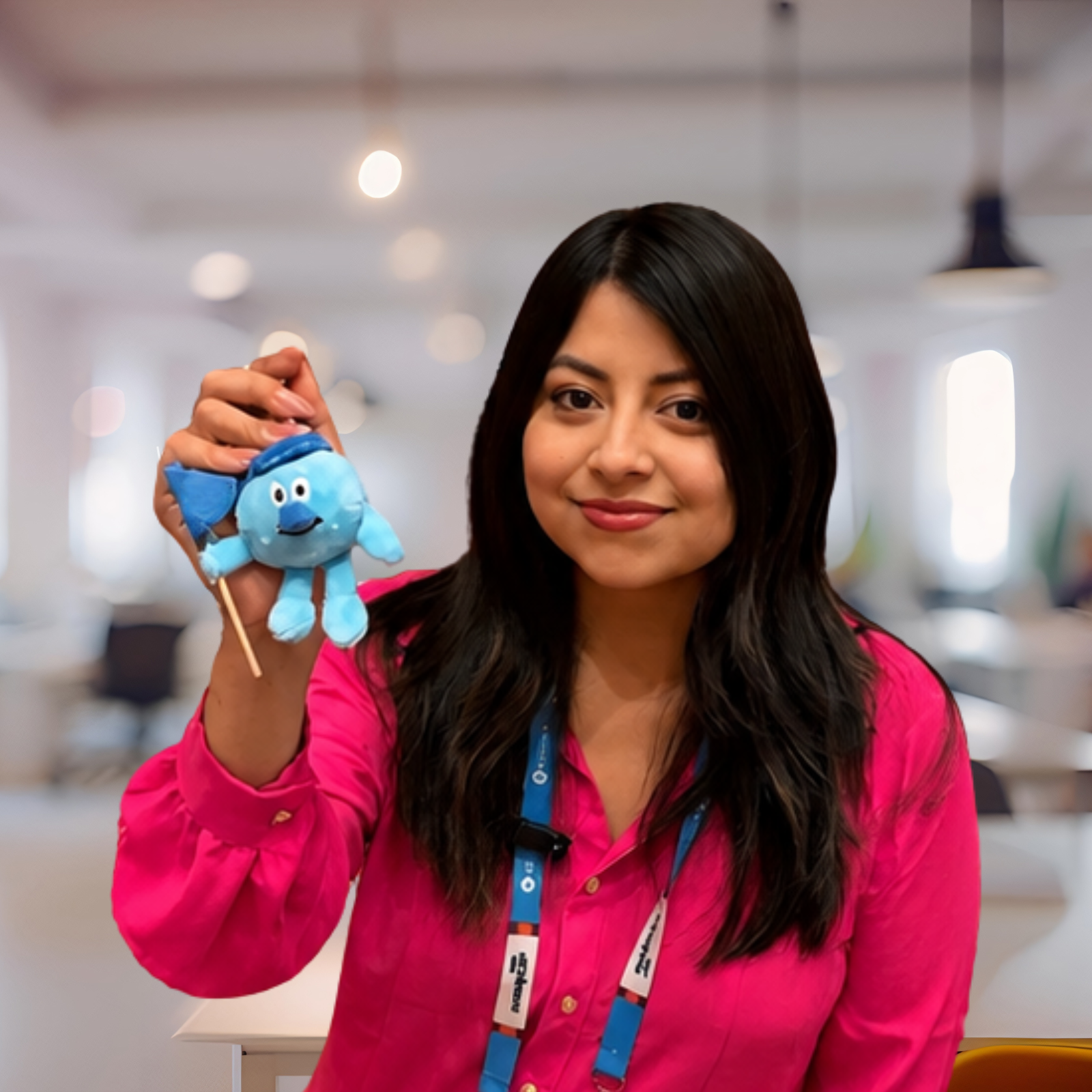 Woman in a bright pink shirt holding a small blue plush toy