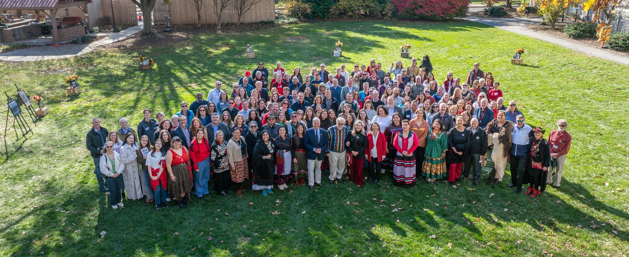 Group photo of diverse people gathered outdoors on a grassy area.