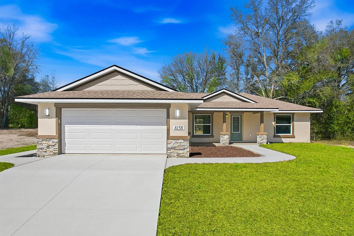 Front view of a neutral ranch-style home with stone wainscoting and a two-car garage.