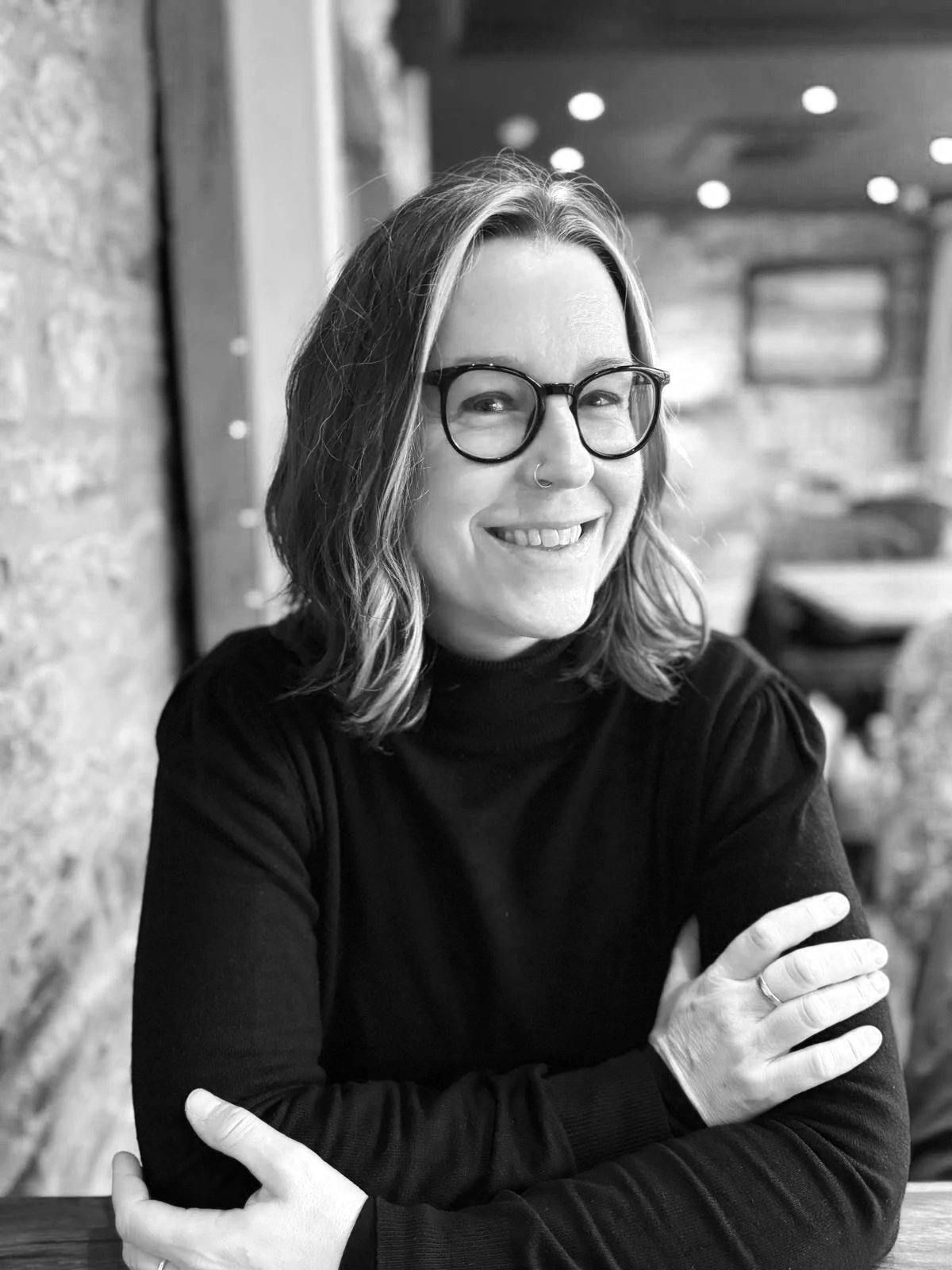 Tree Blackmore sitting in a cafe. Her arms are gently crossed and she is smiling at the camera.