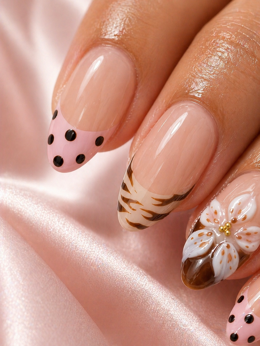 Close-up of manicured nails with floral and animal print designs on a shiny surface.