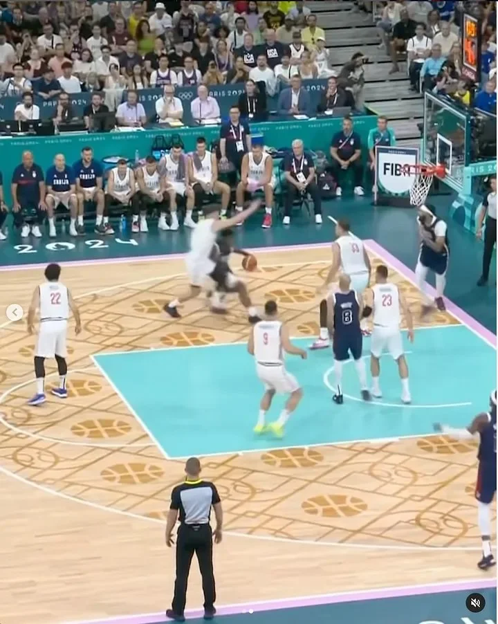  The basketball court from the Olympics with a basketball pattern on the floor and a blue rectangle 