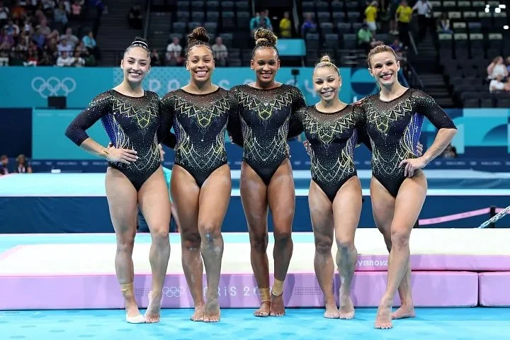  Gymnasts from Team Brazil wearing black and blue uniforms with tons of crystals. 
