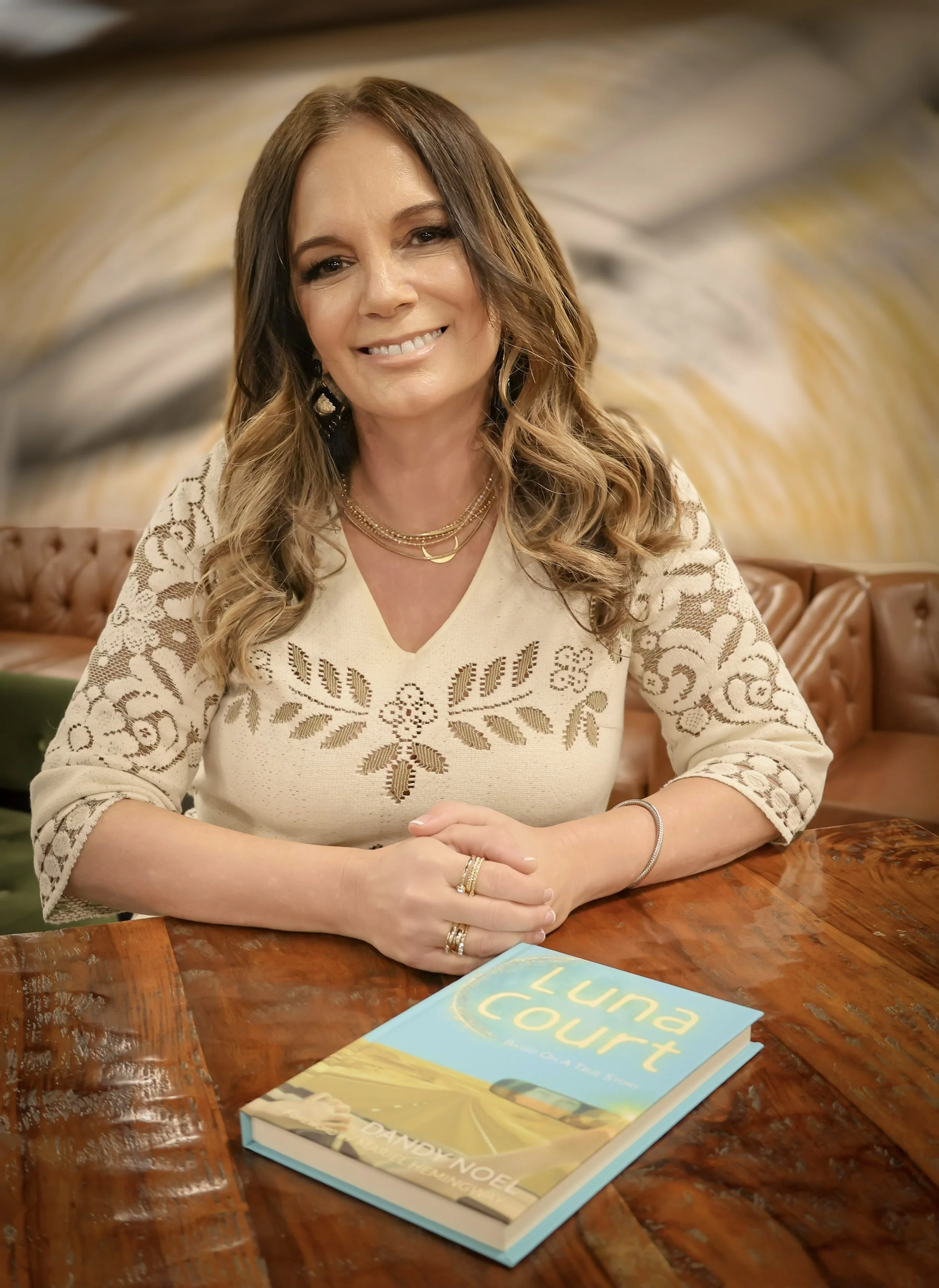 Author Dandy Noel sitting at a table with her book